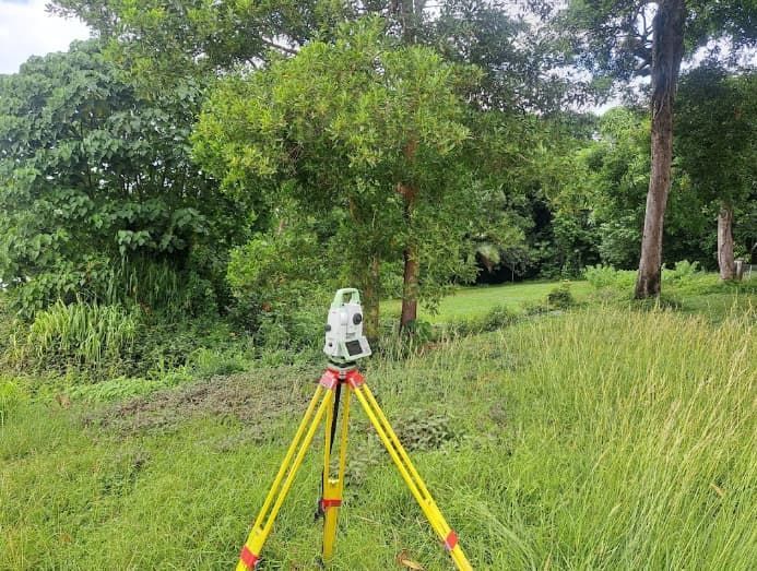 A Tripod Is Sitting In The Middle Of A Grassy Field — TerraModus Surveying In Bayview Heights, QLD