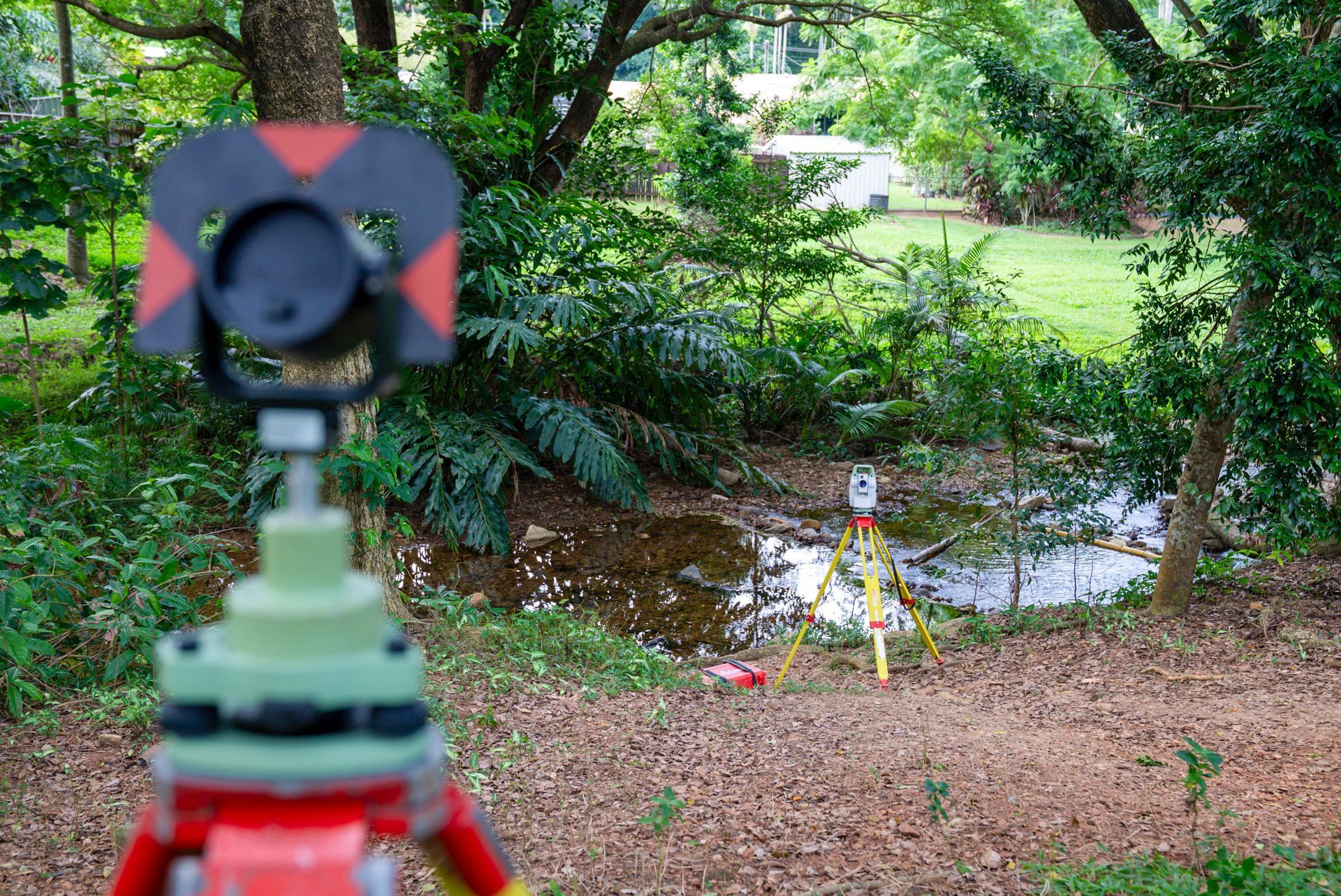 A Theodolite Is Sitting On A Tripod On The Side Of A Road — TerraModus Surveying In Cairns, QLD