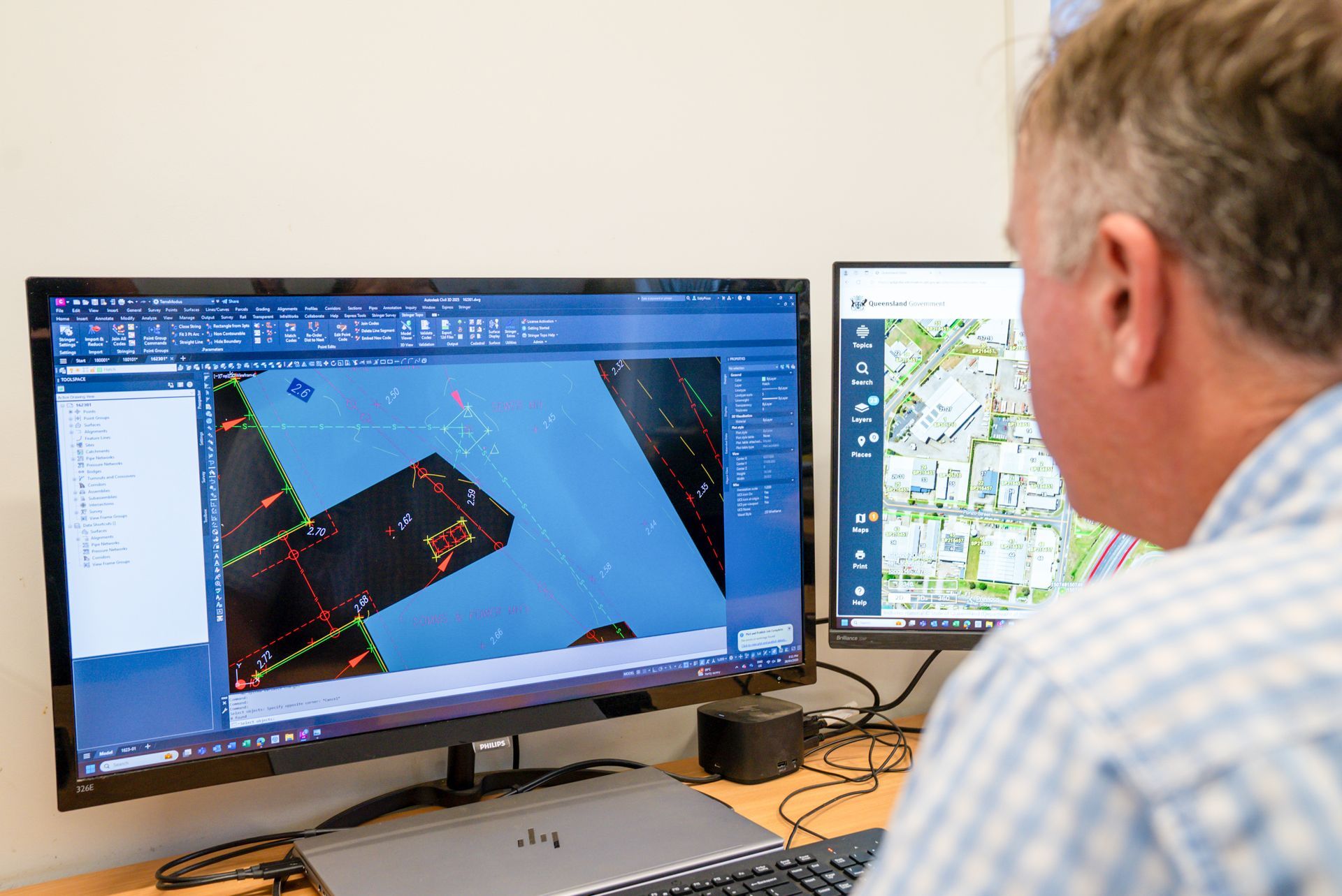 A Man Is Standing Next To A Theodolite On A Tripod And Looking At A Clipboard — TerraModus Surveying In Douglas Shire, QLD