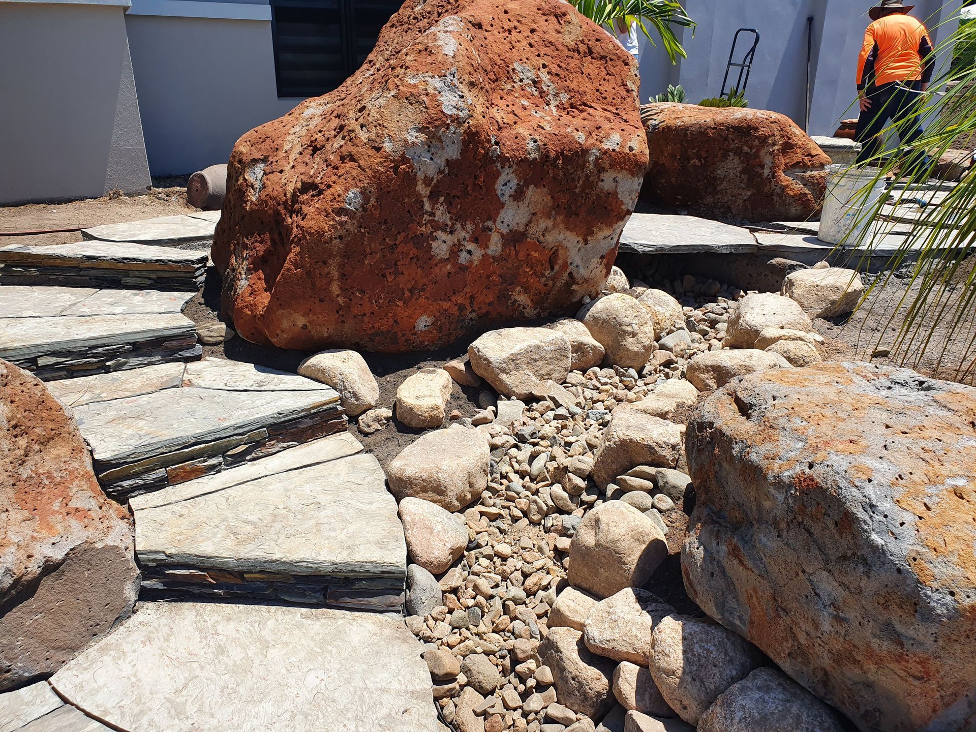 A Child Stands by Metal Support Poles Near a Textured Stone Wall — High End Stone Masons in West End, QLD