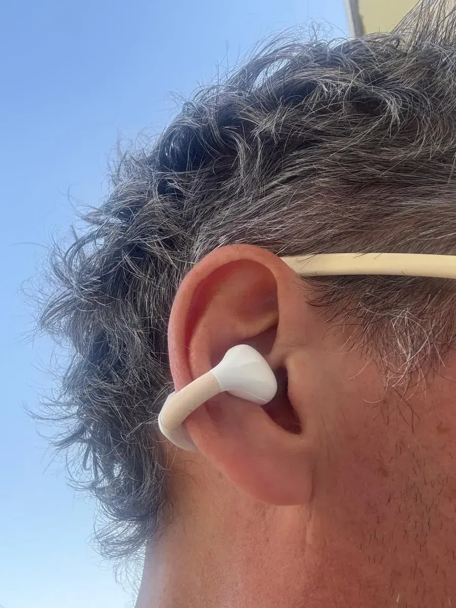 Auriculares inalámbricos blancos en estuche de carga, con pantalla digital de batería.