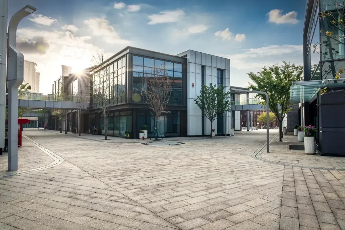 Core One Construction | Modern buildings with glass and white facades, interconnected by walkways, on a cobblestone plaza under a blue sky.