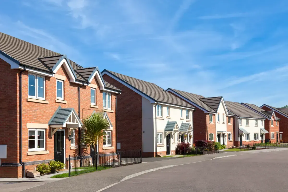 Core One Construction | Row of brick and white houses along a curved street under a blue sky.