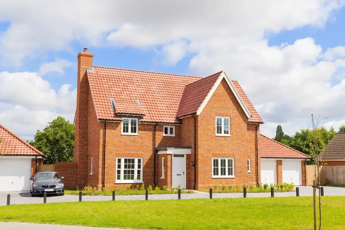 Core One Construction | Brick house with red tile roof and attached garage on a sunny day.
