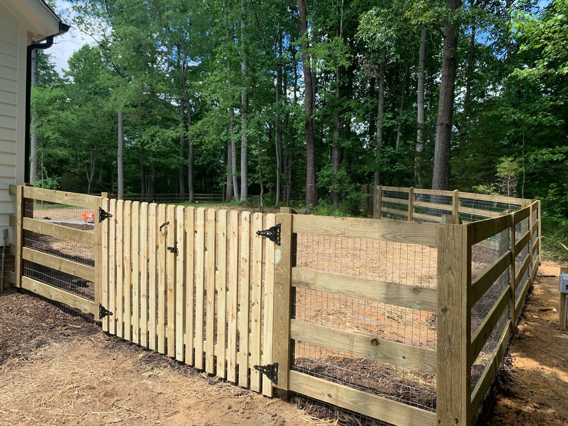 A wooden fence with a gate in the backyard of a house.