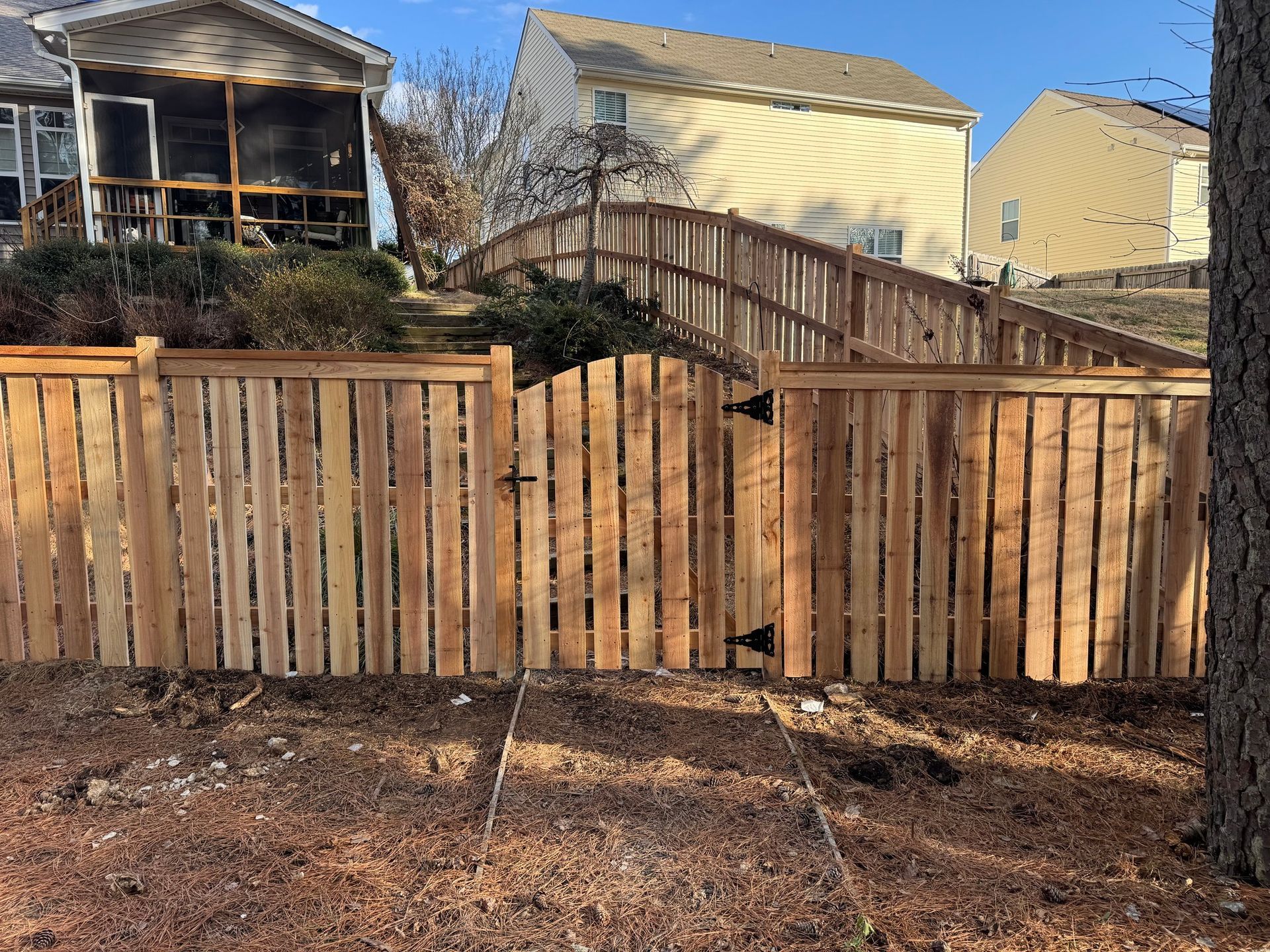 A wooden fence with a gate in front of a house.