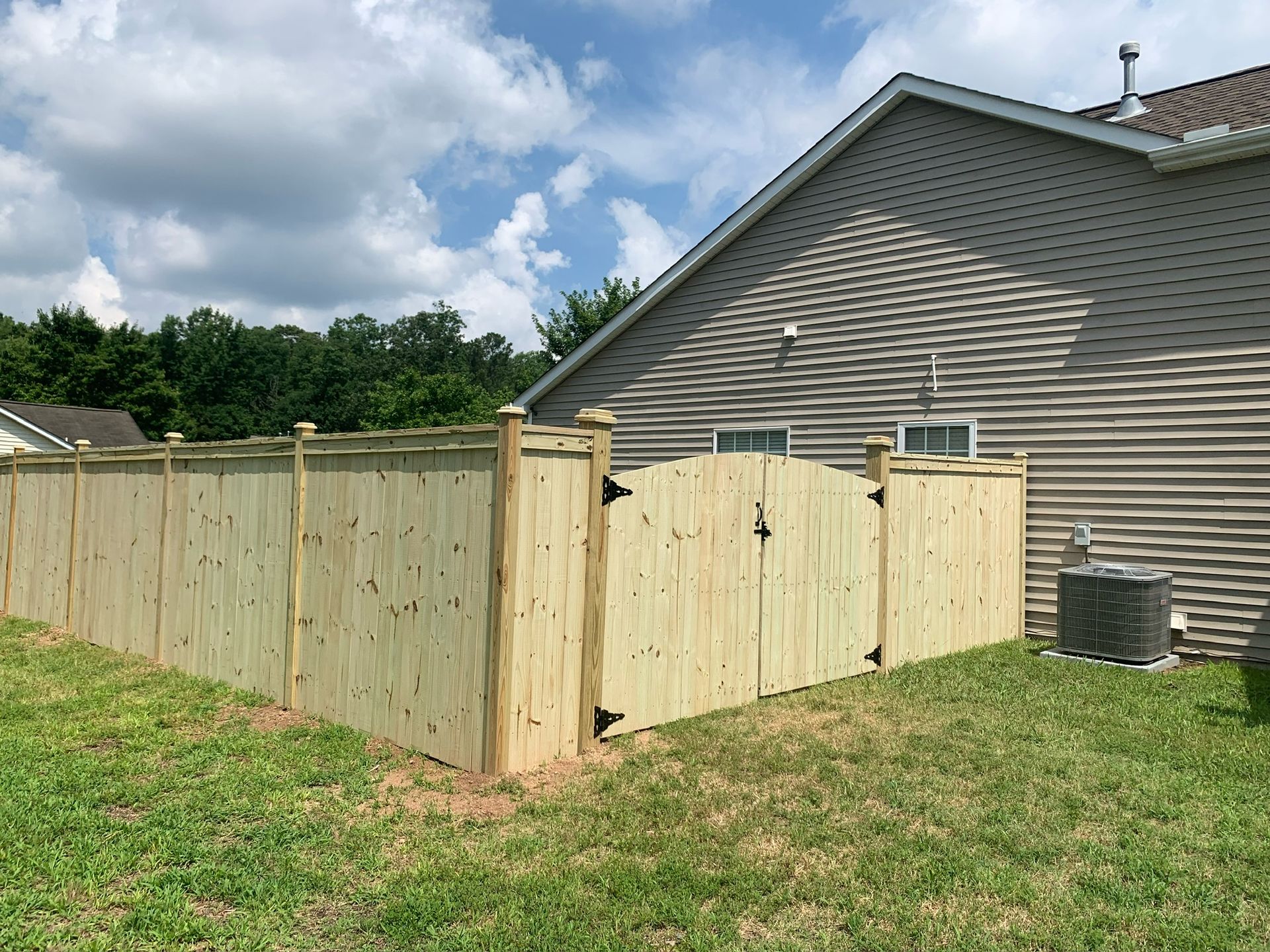 A wooden fence is in the backyard of a house.