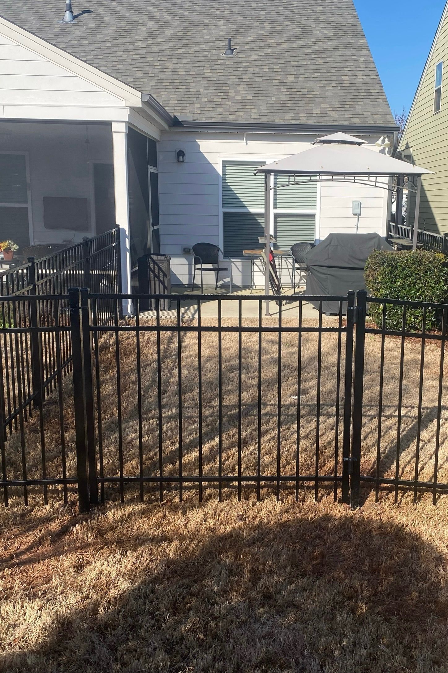 A black metal fence surrounds a patio area in front of a house.