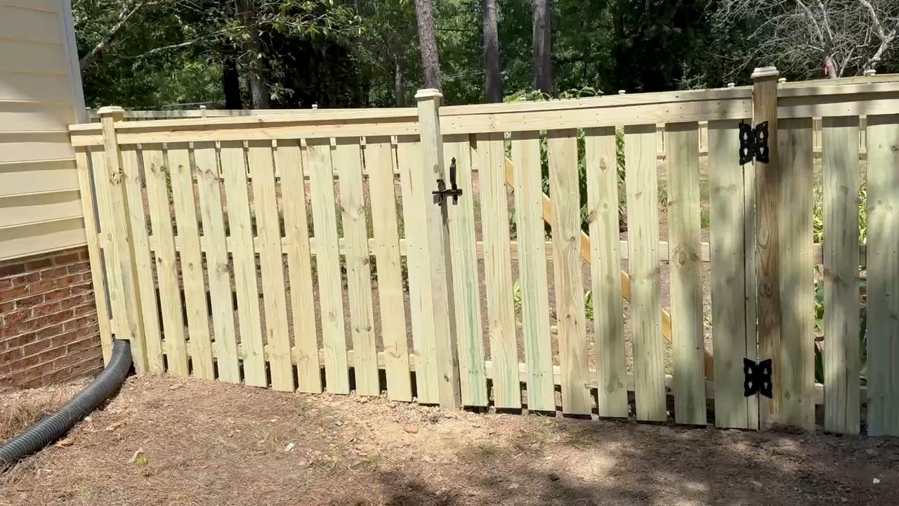 A wooden fence with a gate in the backyard of a house.