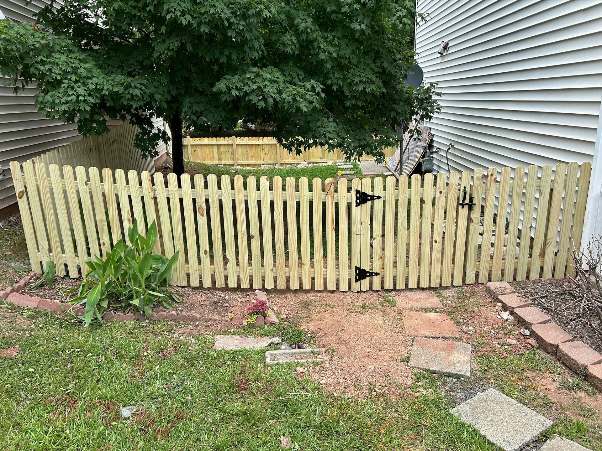 A wooden picket fence with a gate in the backyard of a house.