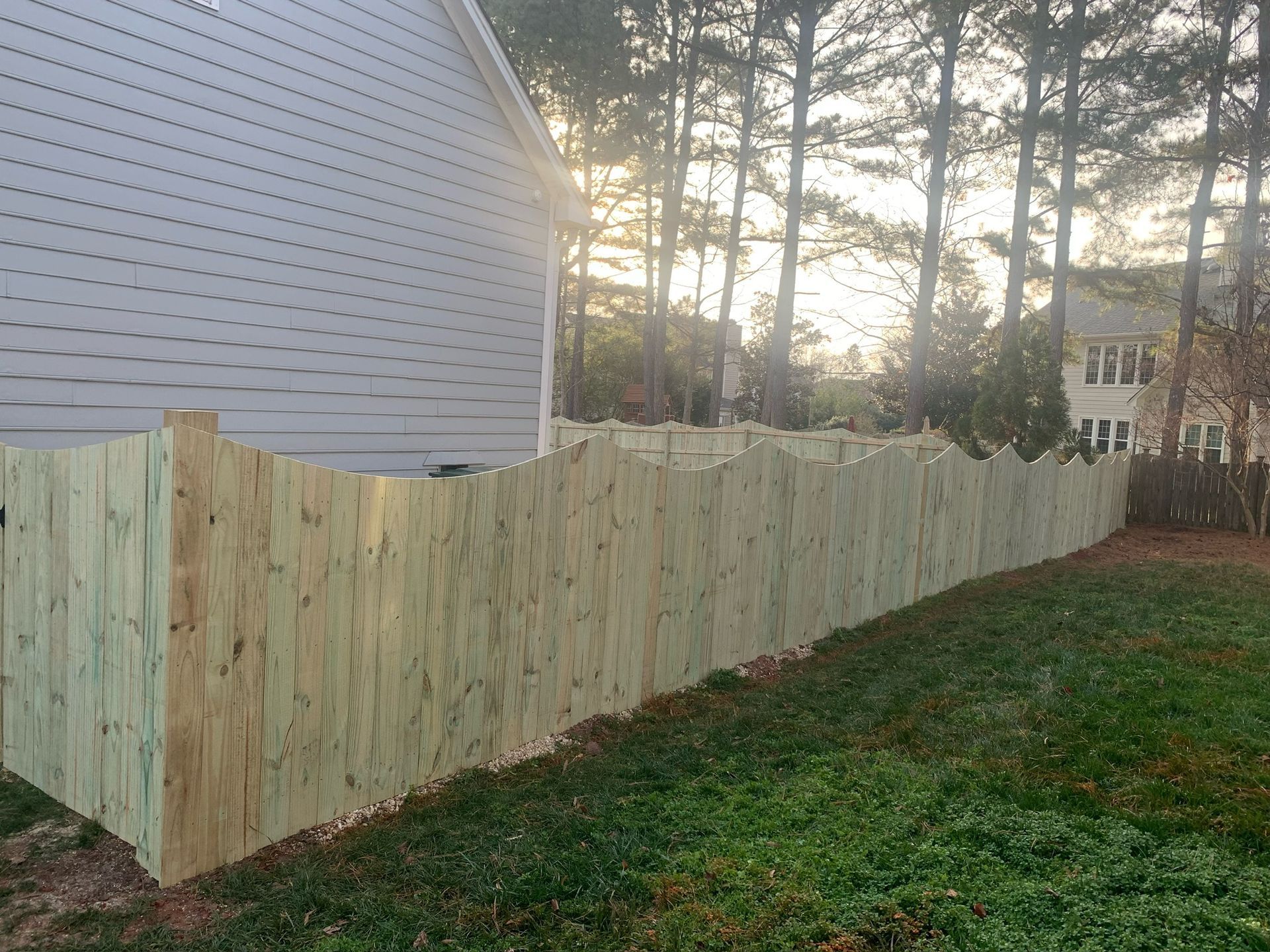 A wooden fence is in the backyard of a house.