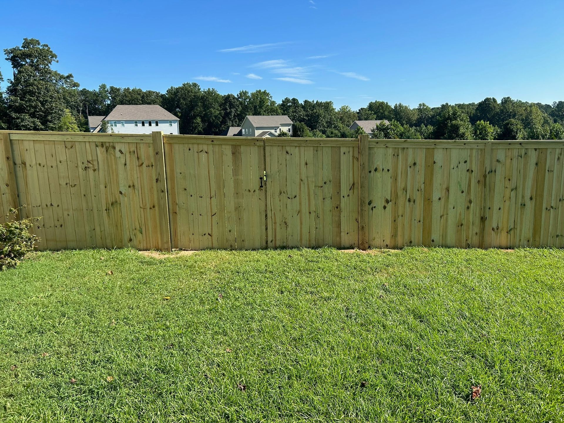 A wooden fence is in the middle of a lush green field.