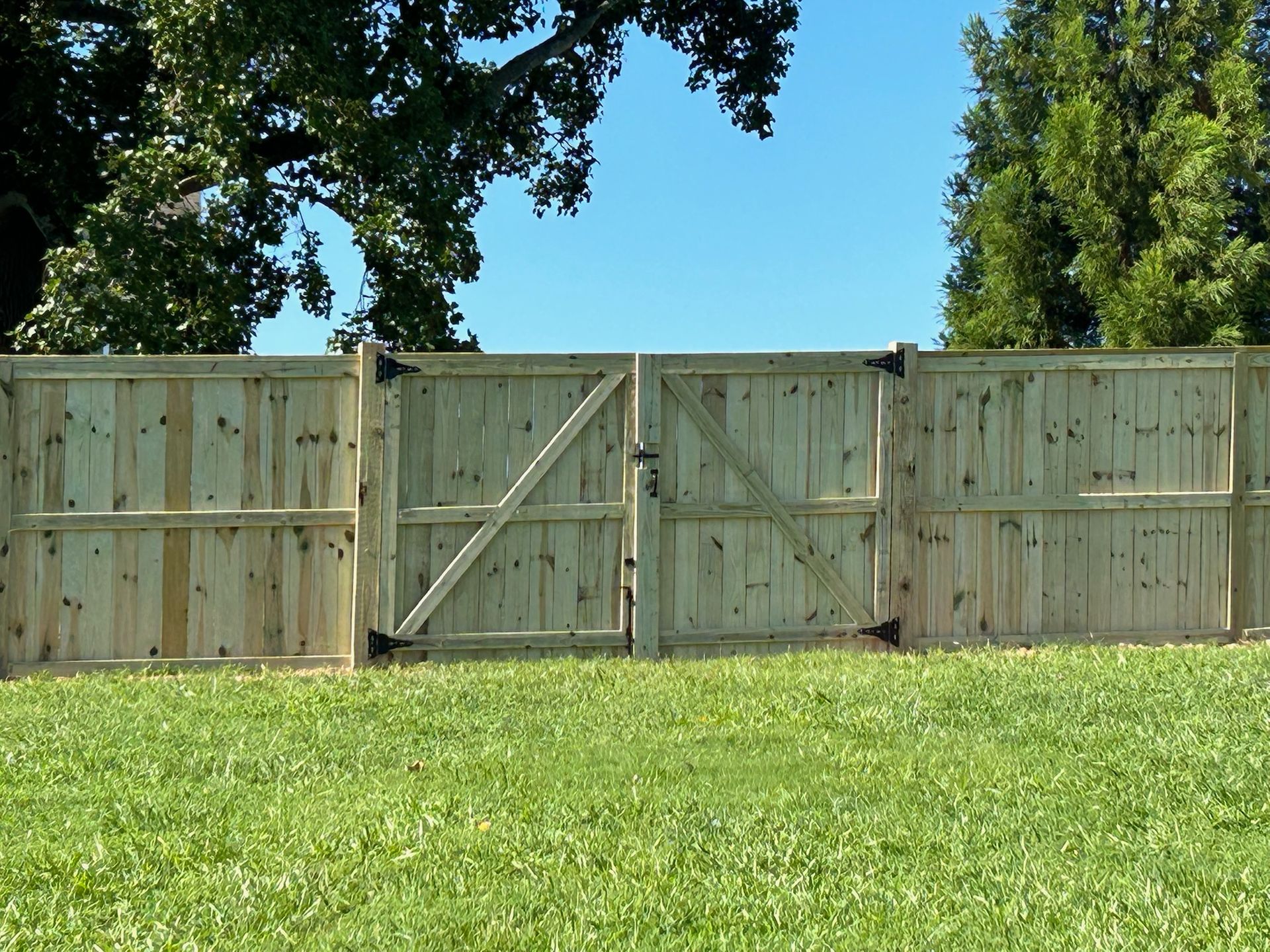 A wooden fence surrounds a lush green field