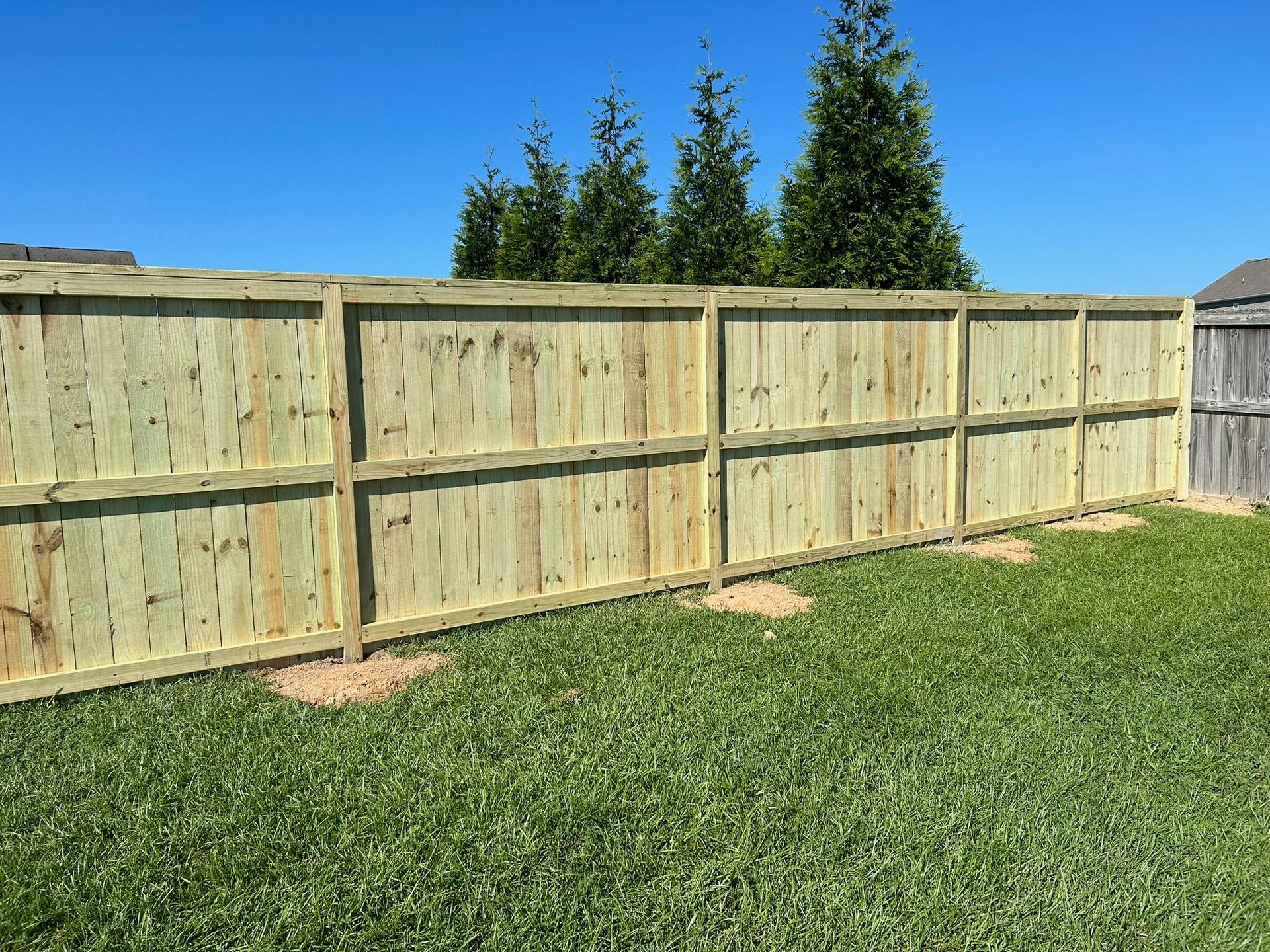 A wooden fence is sitting on top of a lush green lawn.