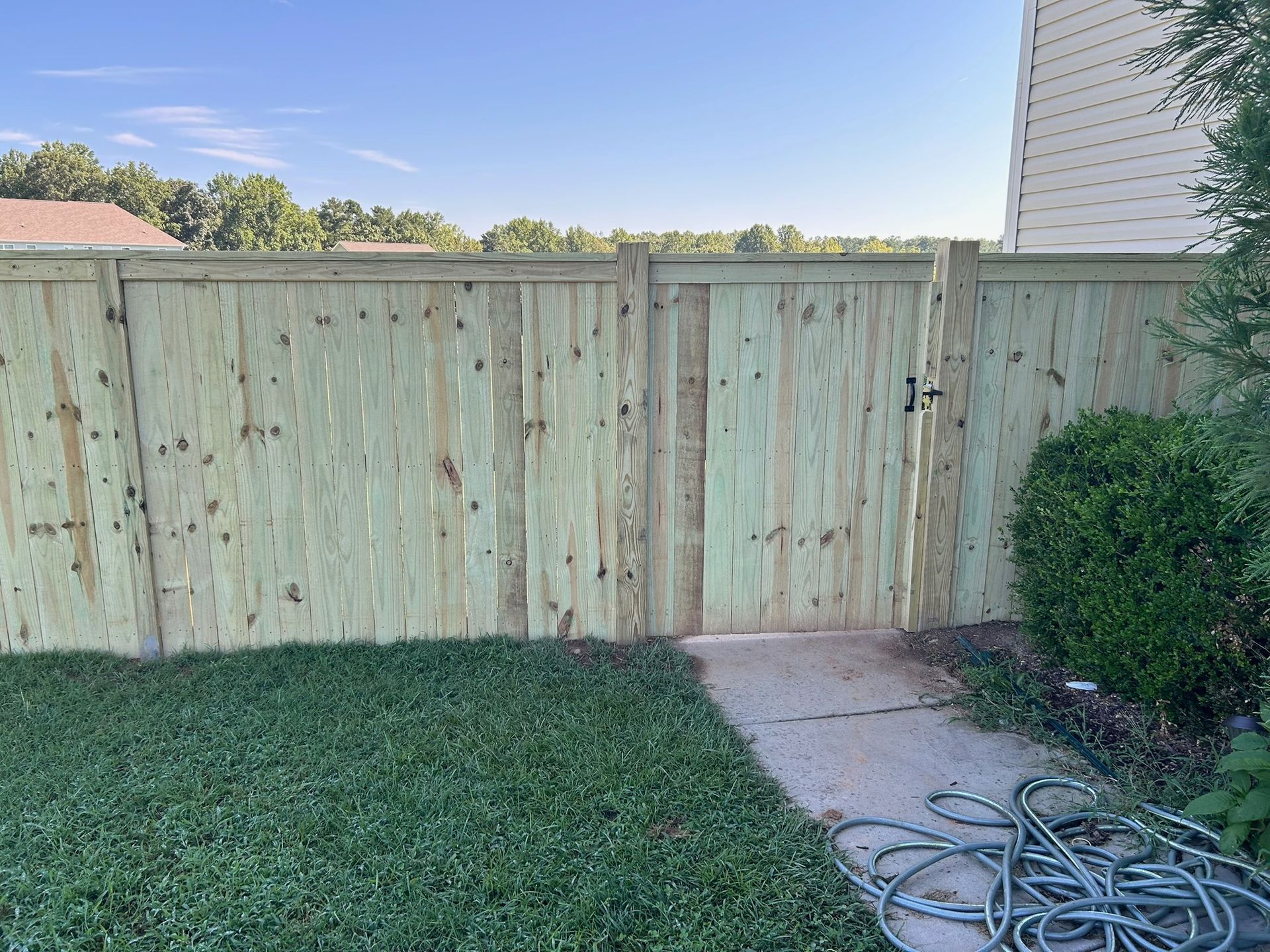 A wooden fence with a gate in the backyard of a house.