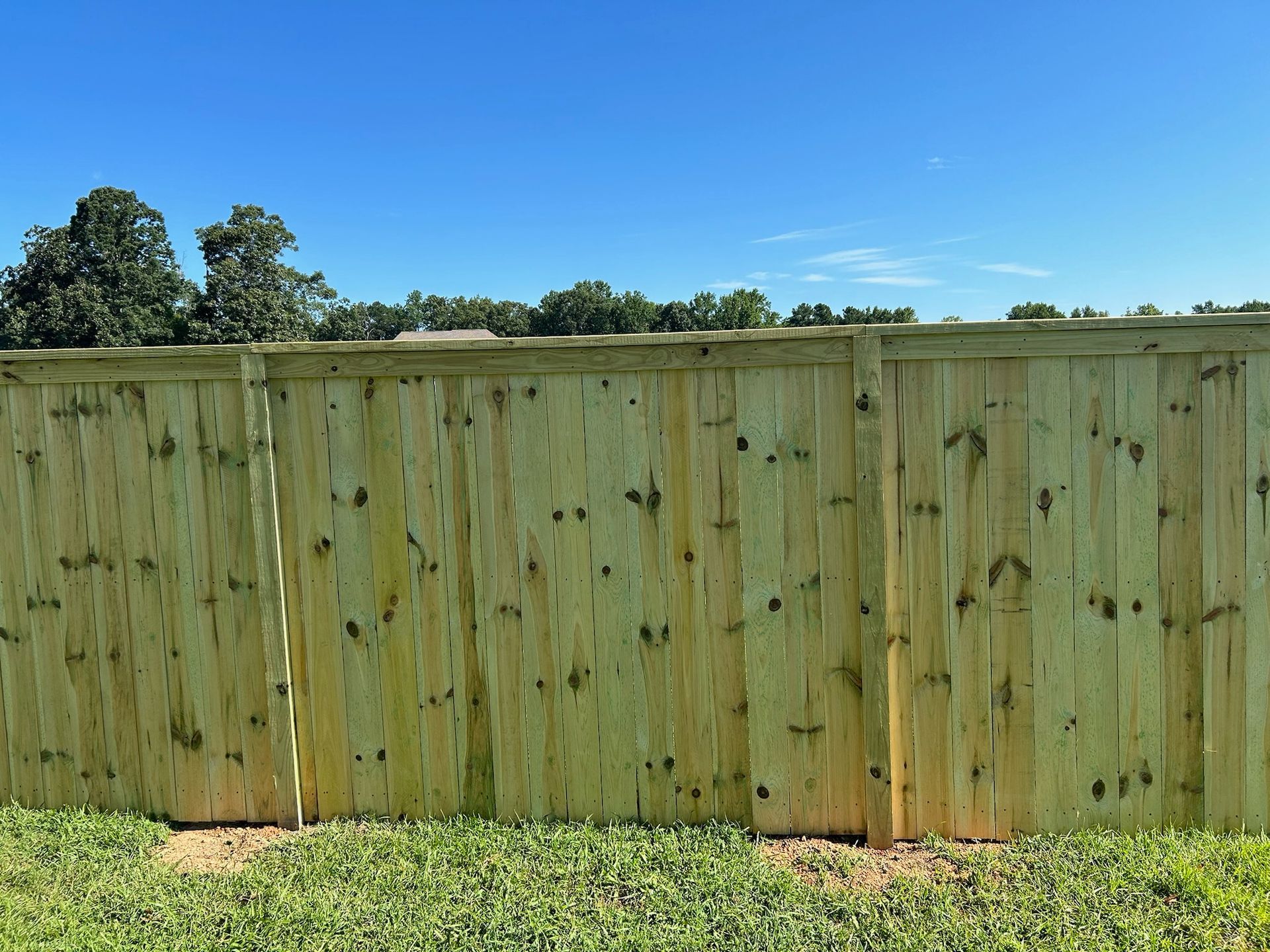 A wooden fence is sitting in the middle of a lush green field.
