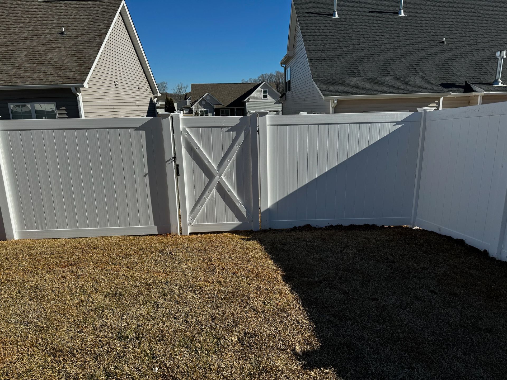 A white fence with a gate in the backyard