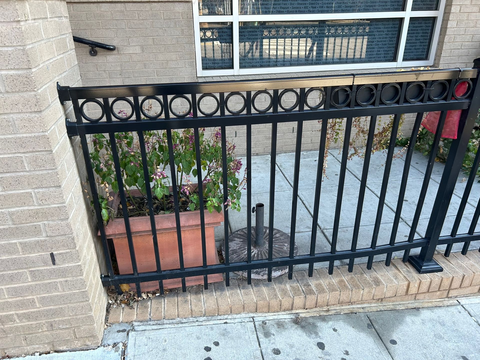 A black metal fence surrounds a brick building with a window.