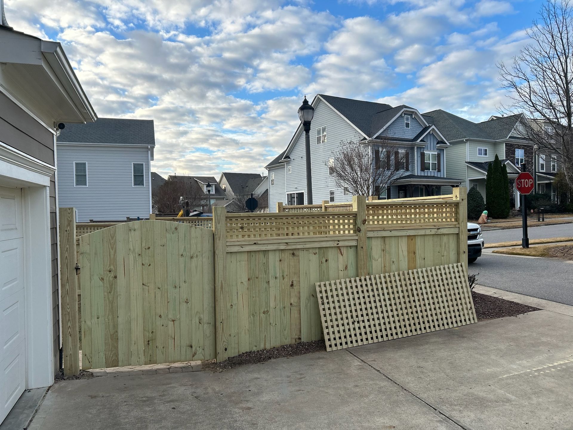 A wooden fence is sitting on the sidewalk in front of a garage.