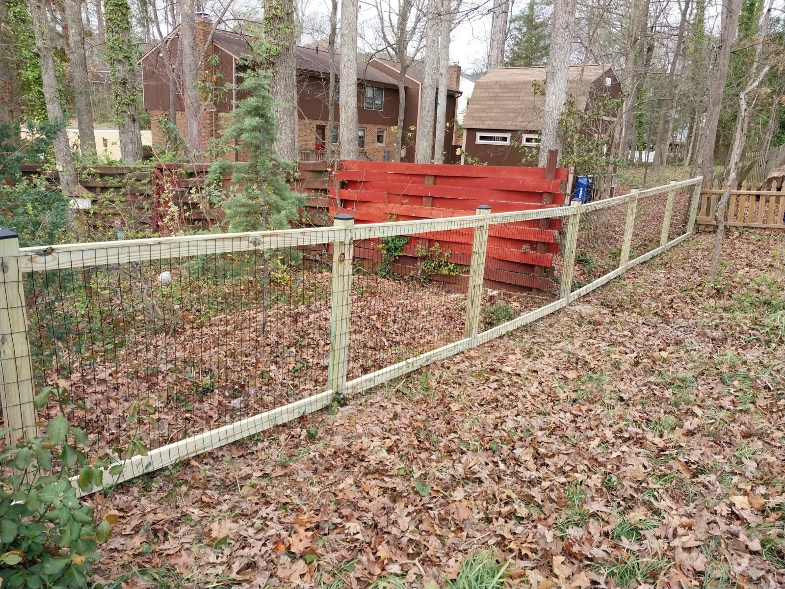 A wooden fence is surrounded by leaves in a yard.