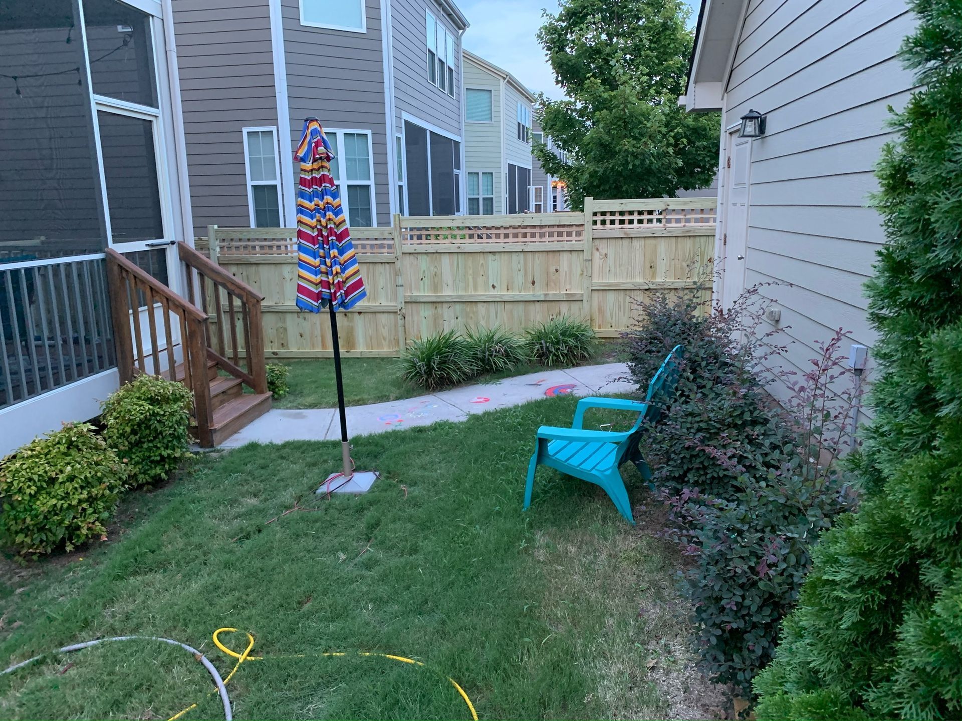 There is a blue chair in the backyard of a house.