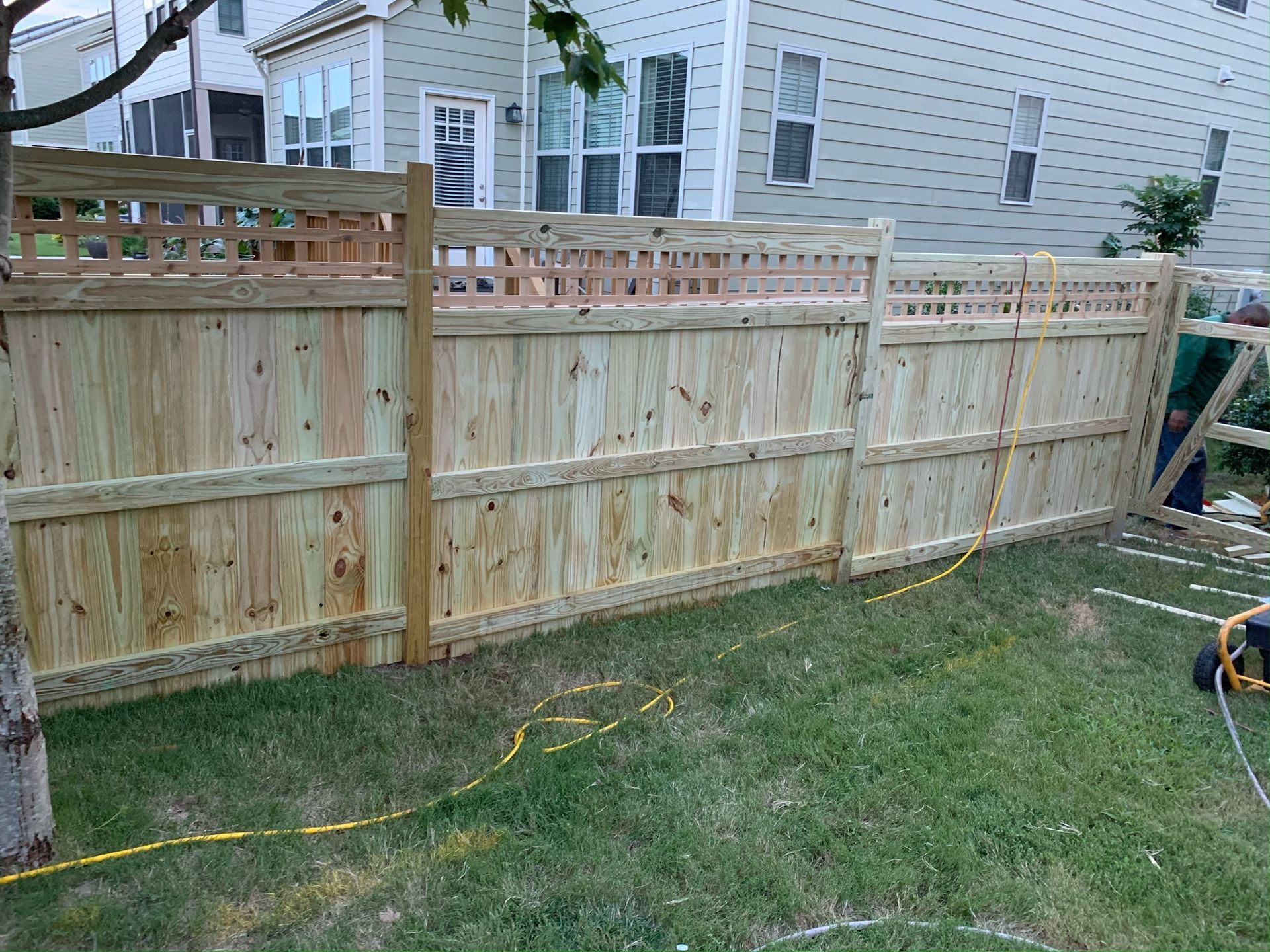 A wooden fence is being built in the backyard of a house.