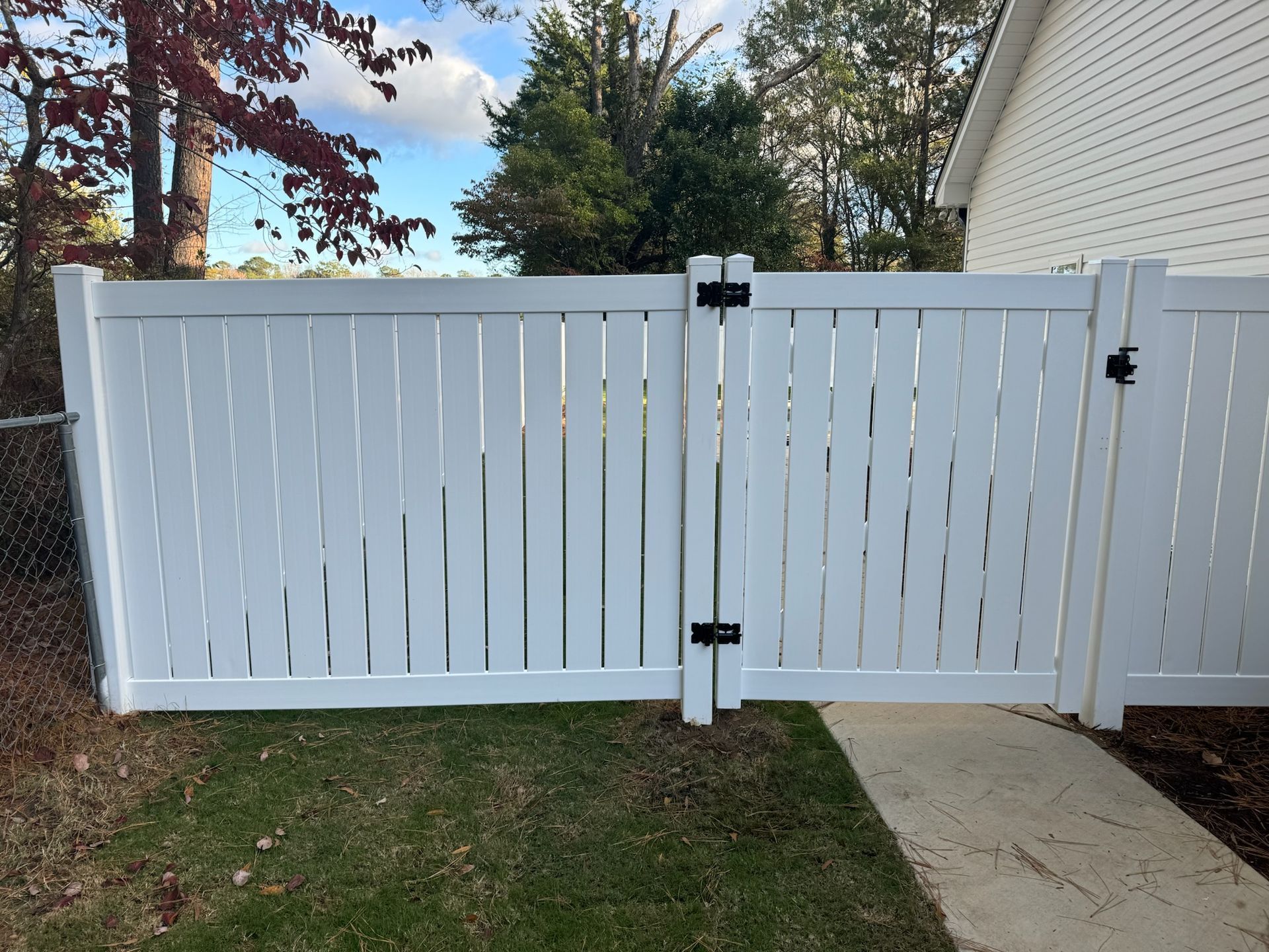 A white fence with a gate in front of a house.