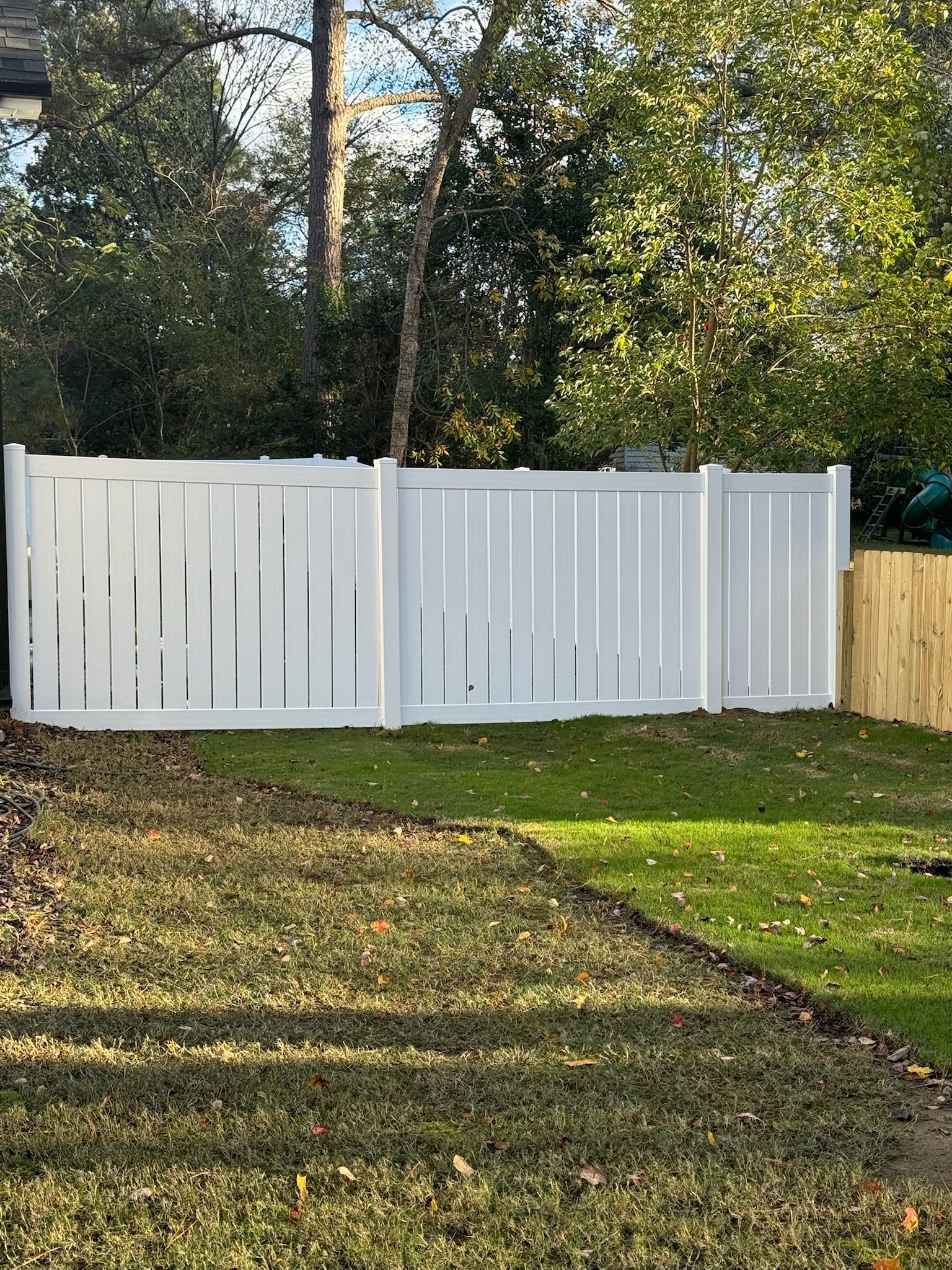 A white fence is in the middle of a lush green yard.