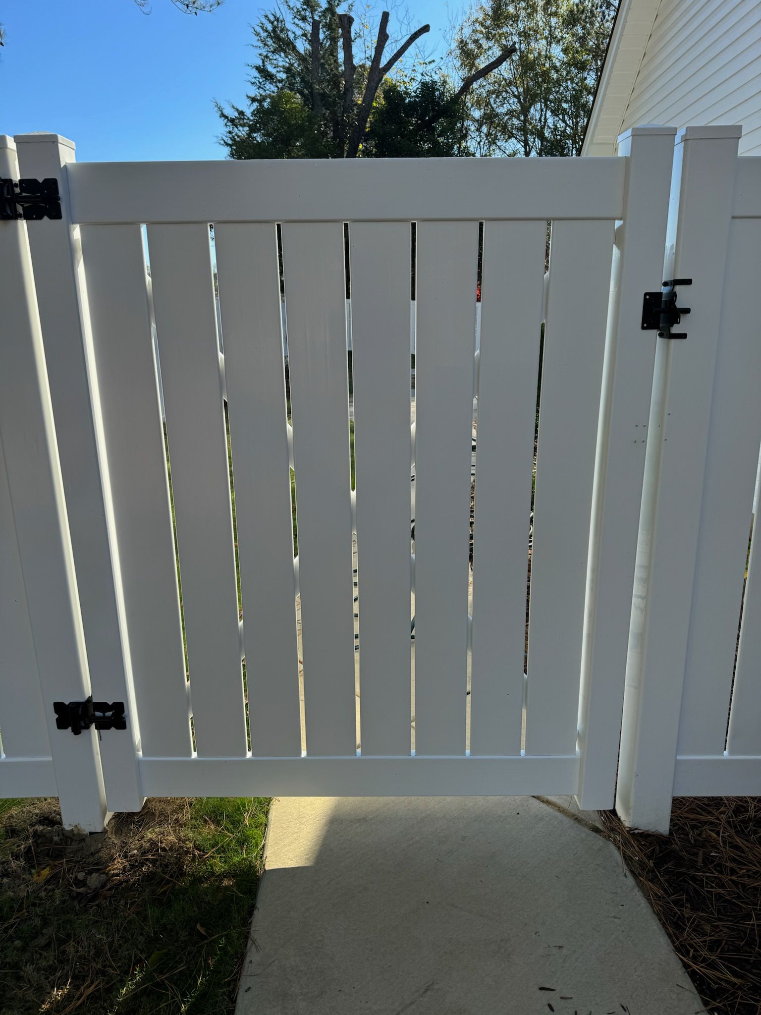 A white fence with a black hinge on it