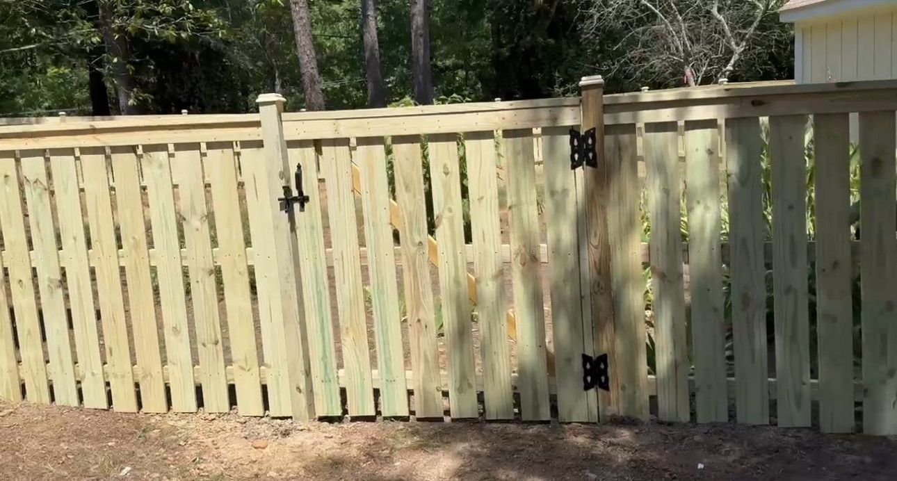 A wooden fence with a gate in the backyard of a house.