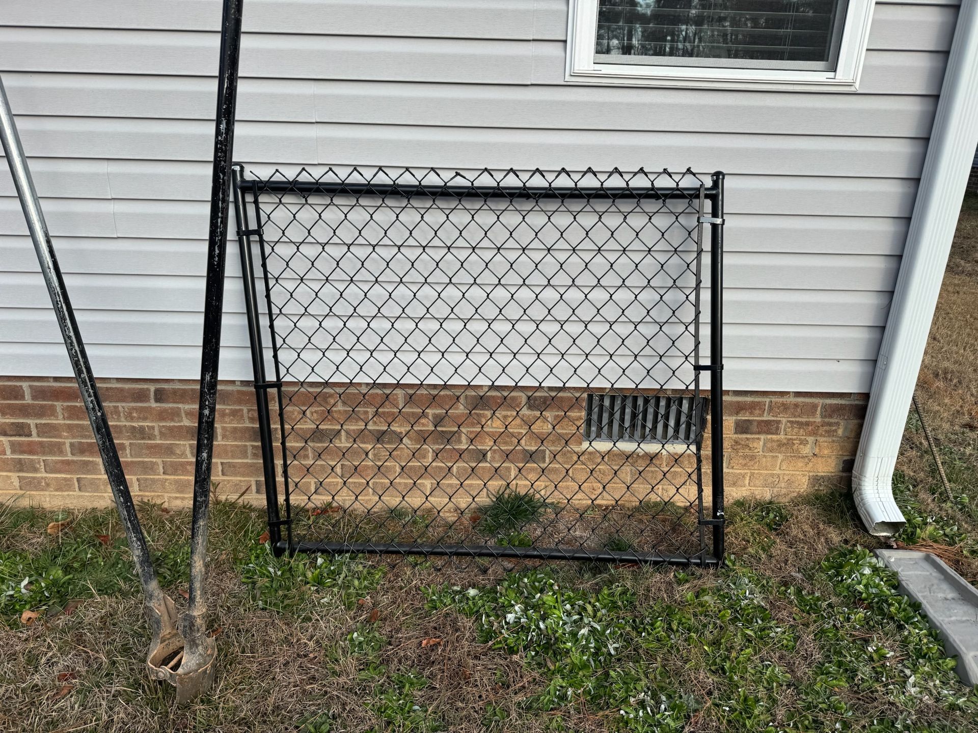A chain link fence is sitting in front of a brick house.