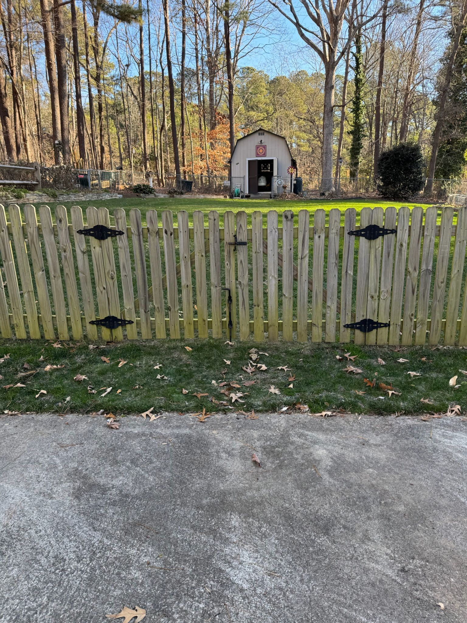 A wooden fence surrounds a yard with a barn in the background.