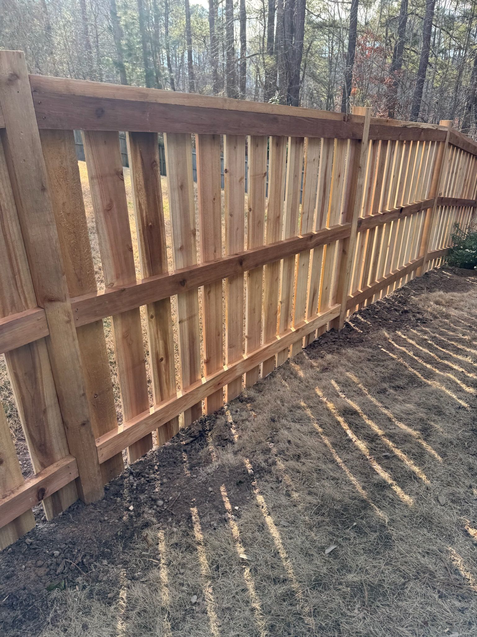 A wooden fence is sitting in the middle of a dirt field.