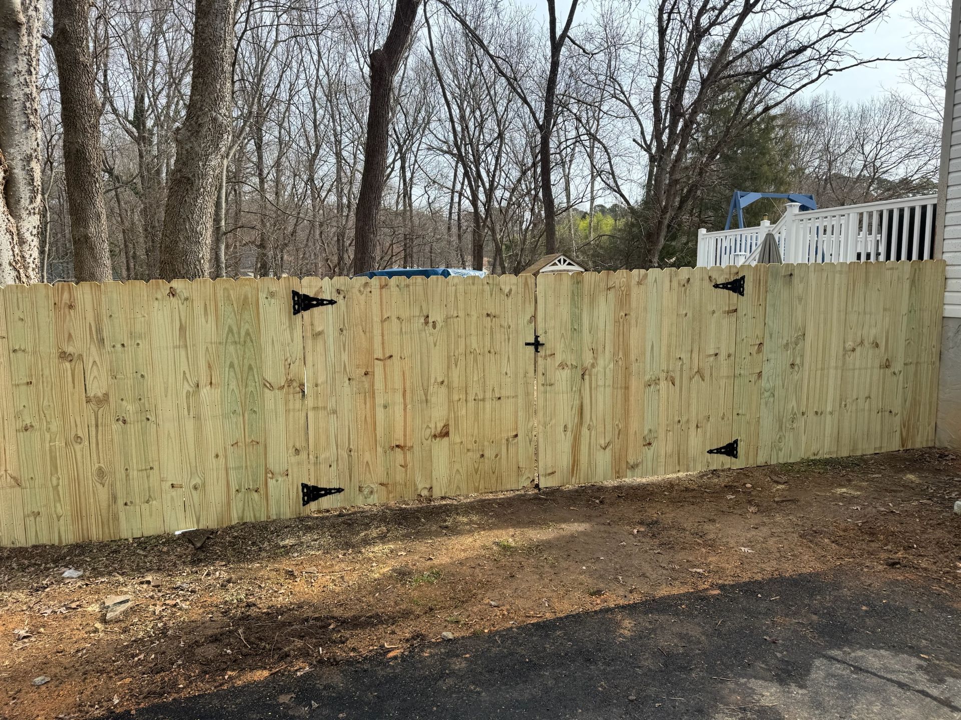 A wooden fence with a gate in the backyard of a house.