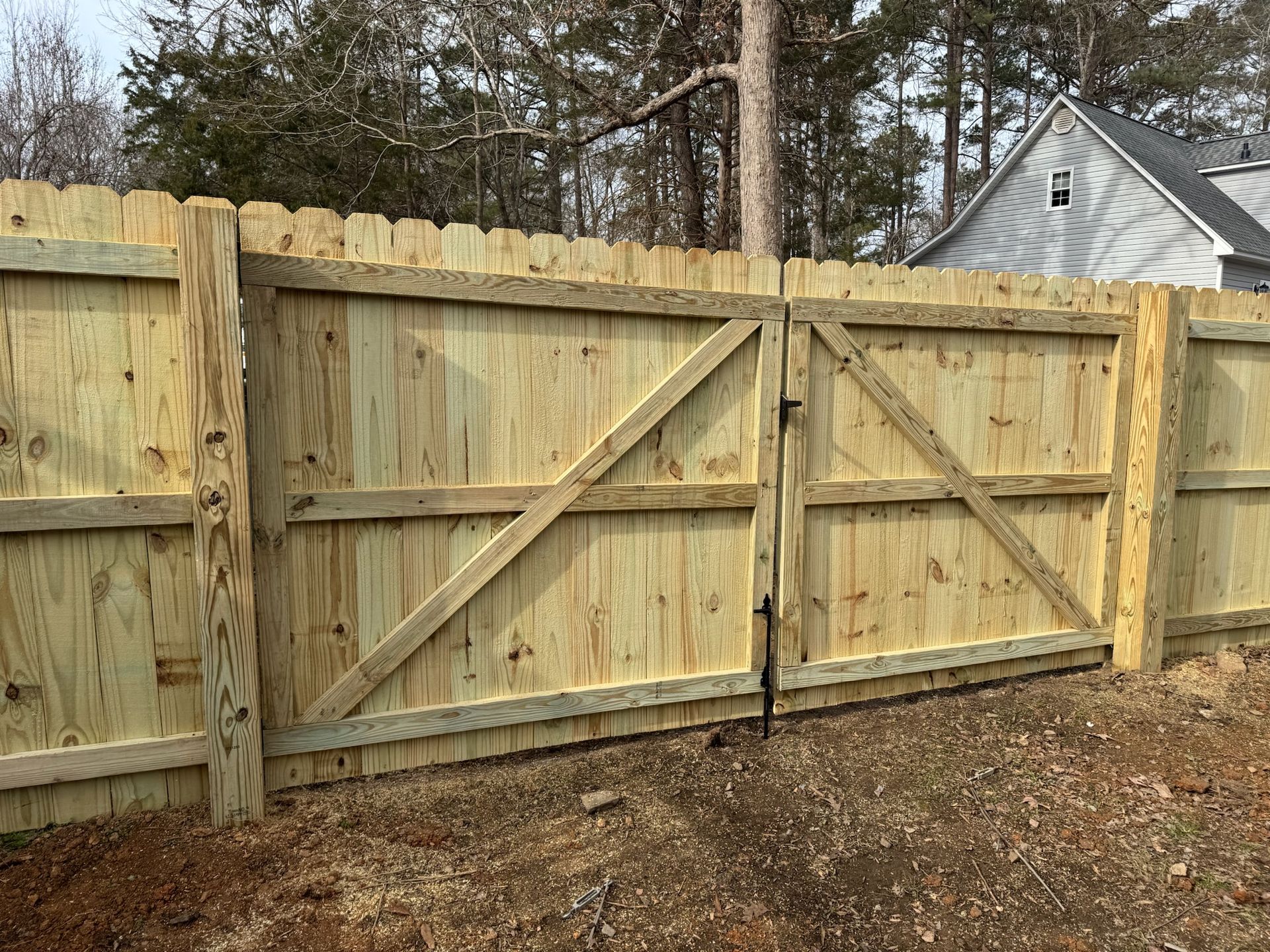 A wooden fence with a gate in the backyard of a house.