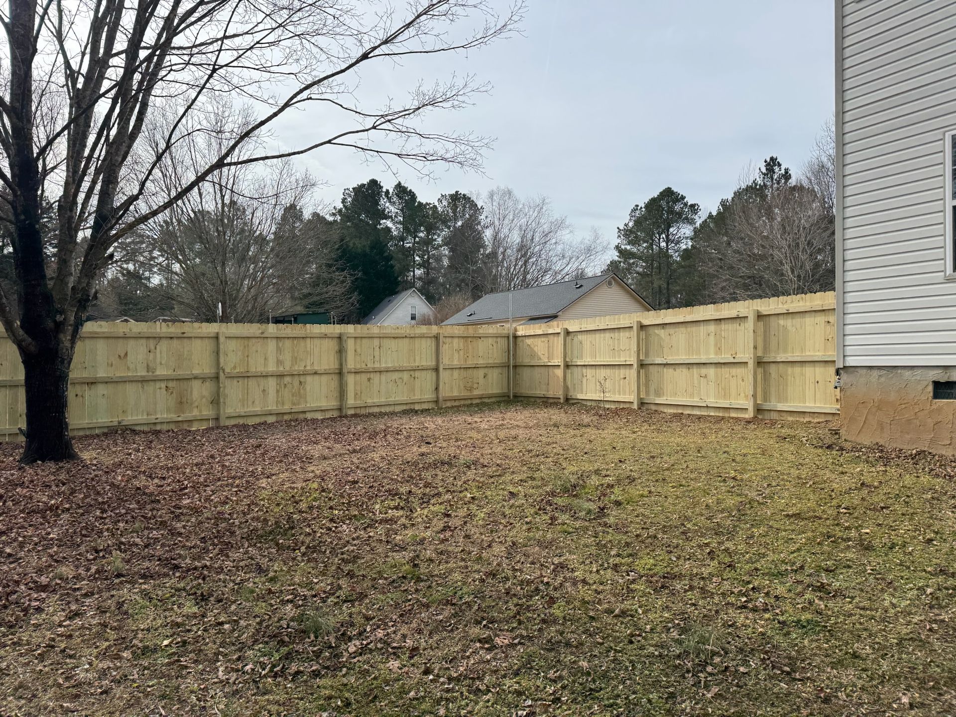 There is a wooden fence in the backyard of a house.