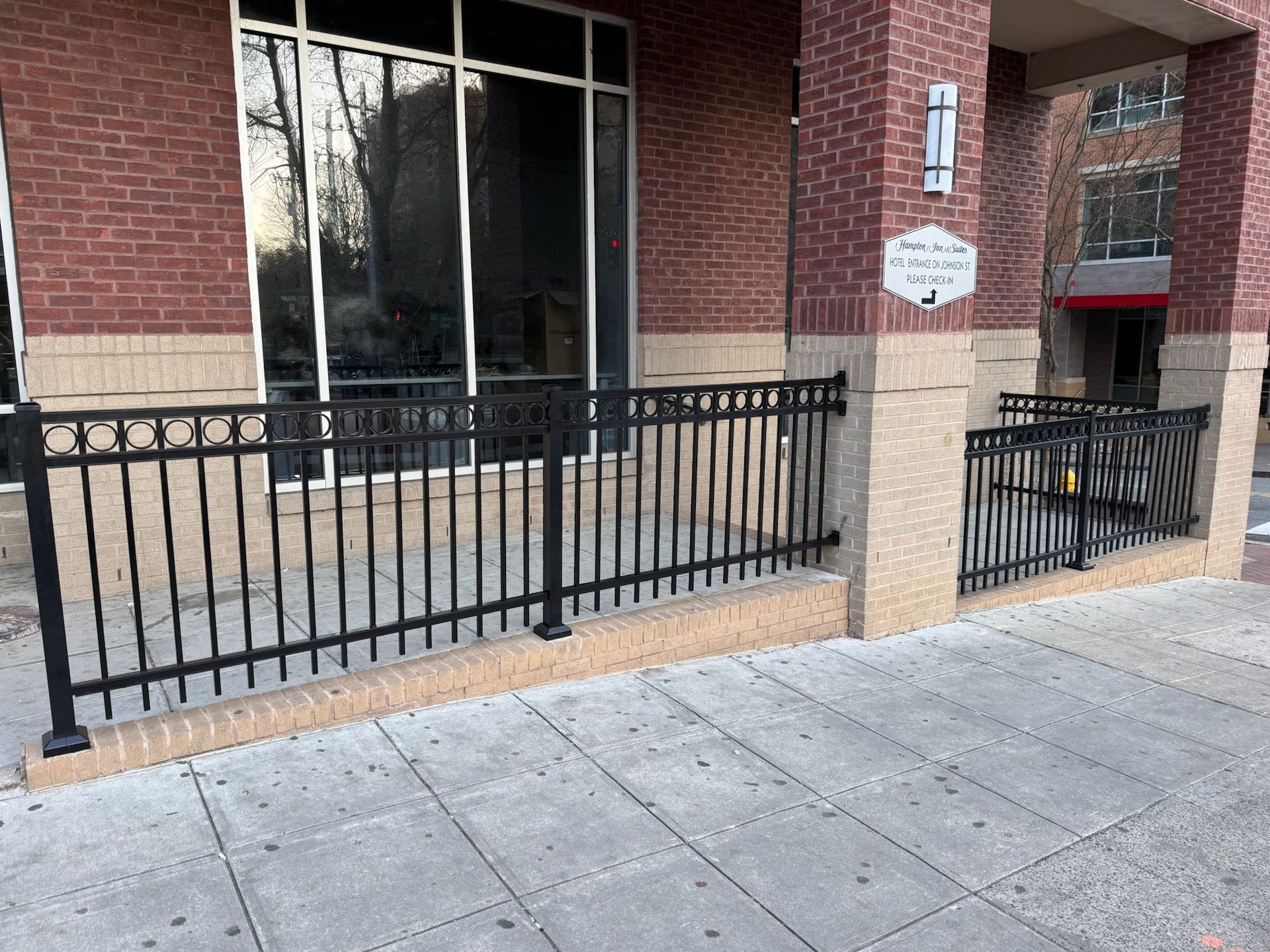 A black fence is in front of a brick building.