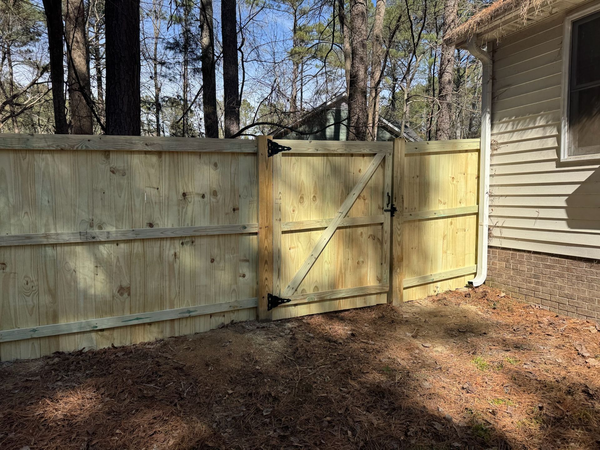A wooden fence with a gate in the backyard of a house.