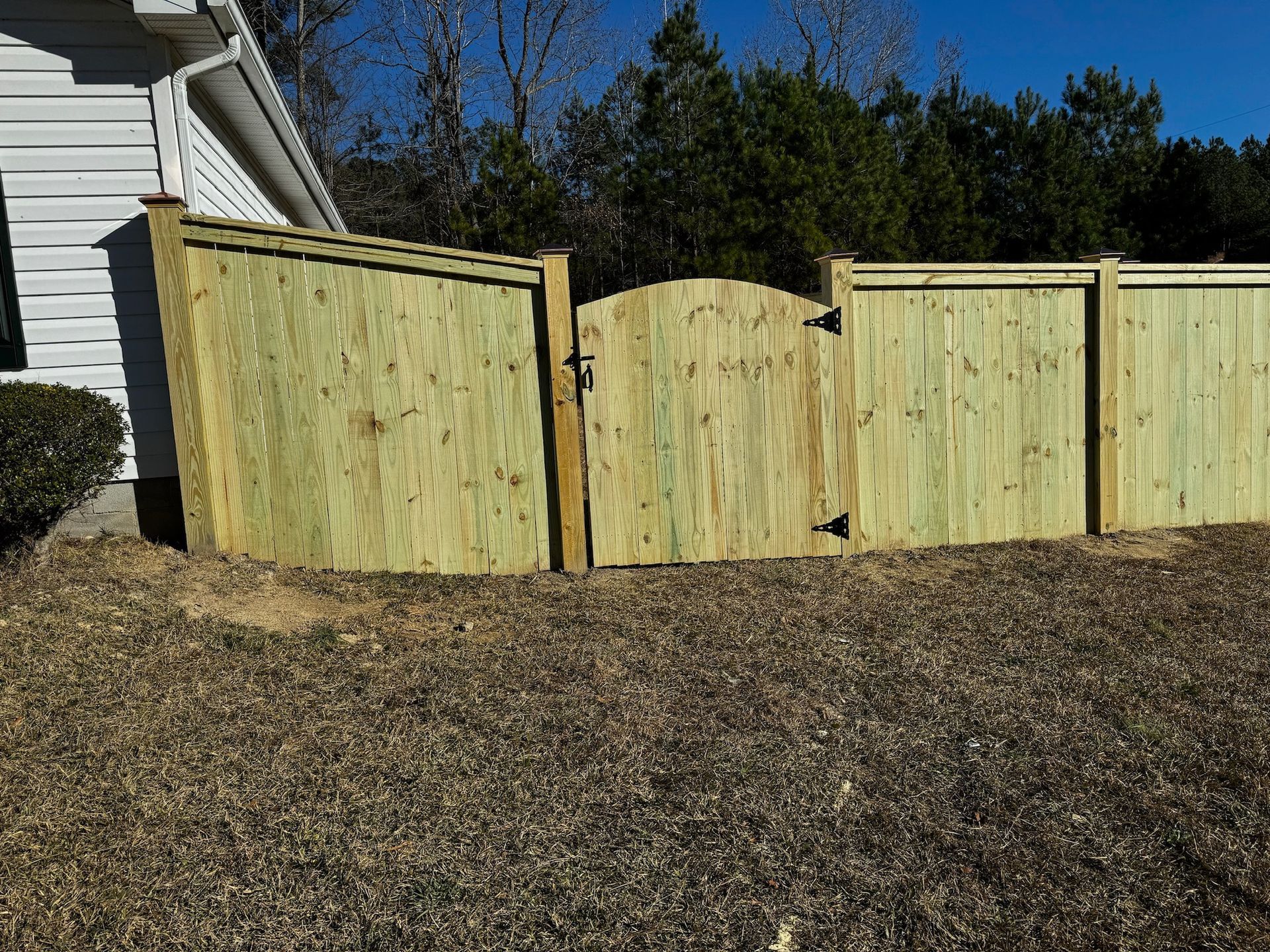 A wooden fence with a gate in front of a house.