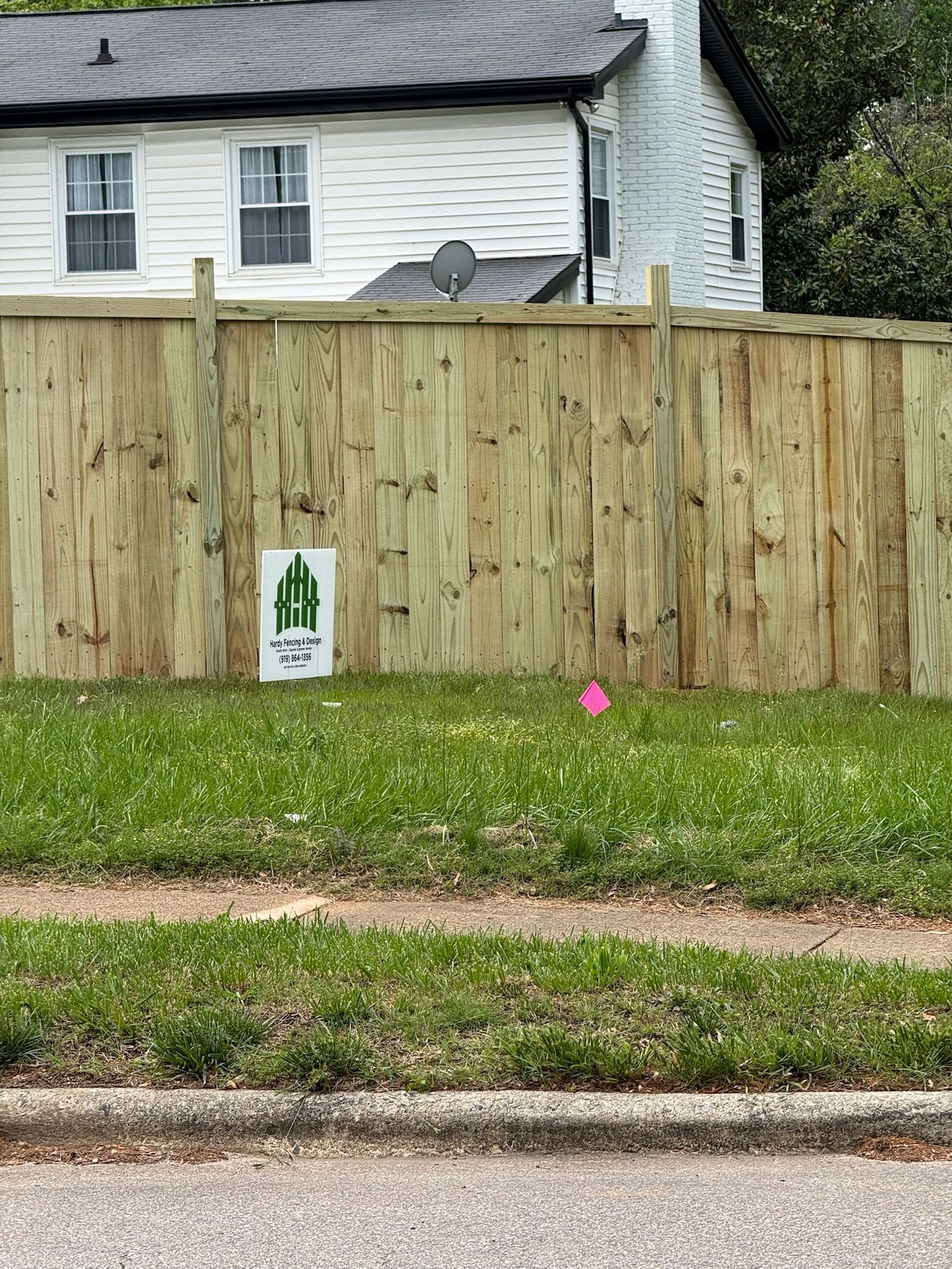 A wooden fence with a cactus sign in front of a house.