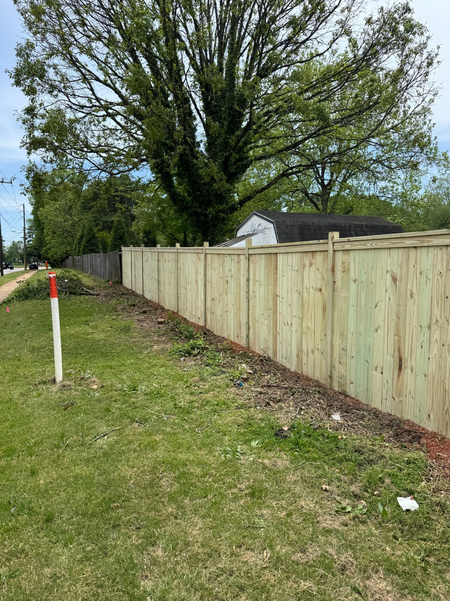 A wooden fence is sitting on top of a lush green field next to a tree.