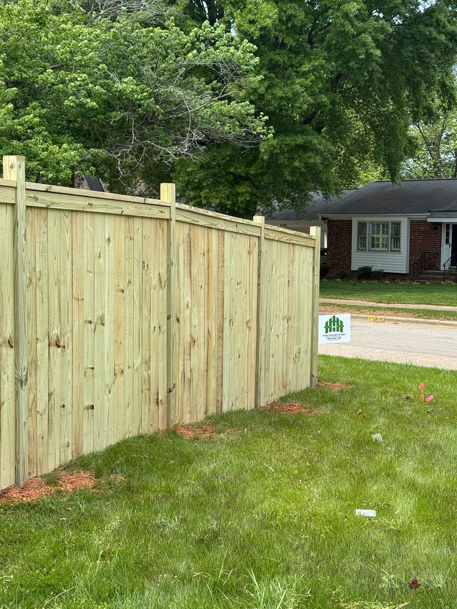 A wooden fence is sitting in the grass in front of a house.