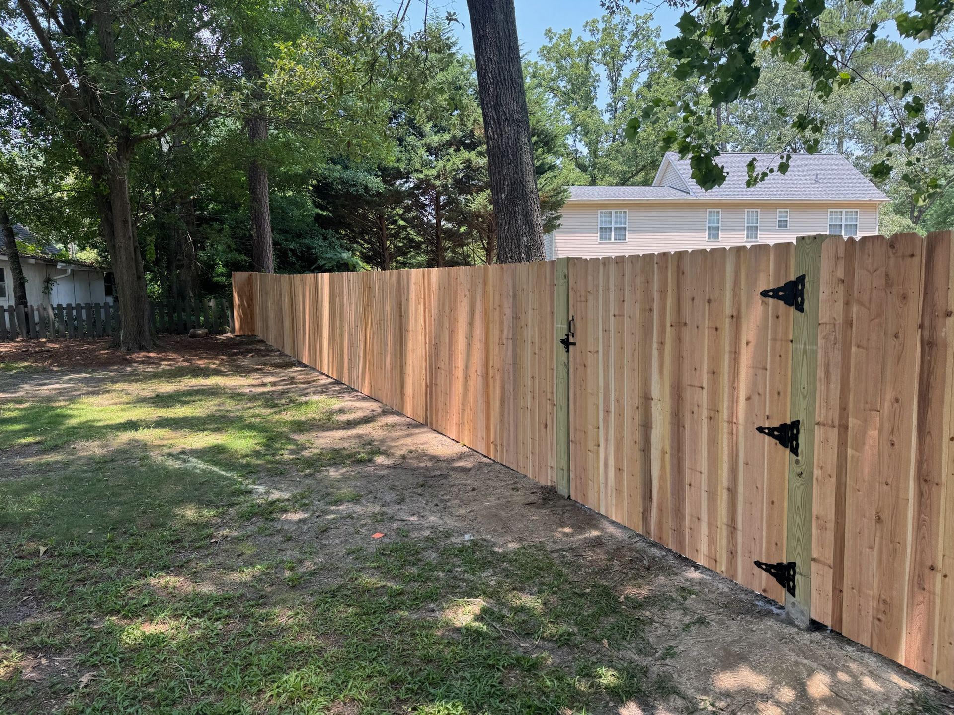 A wooden fence with a gate in the backyard of a house.