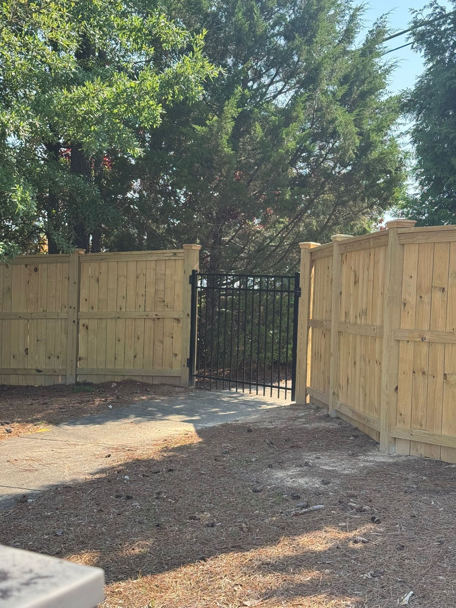 A wooden fence with a gate and trees in the background.