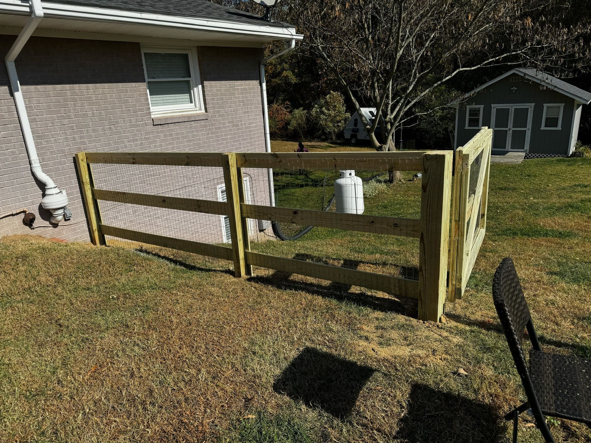 A wooden fence is sitting in the grass in front of a house.