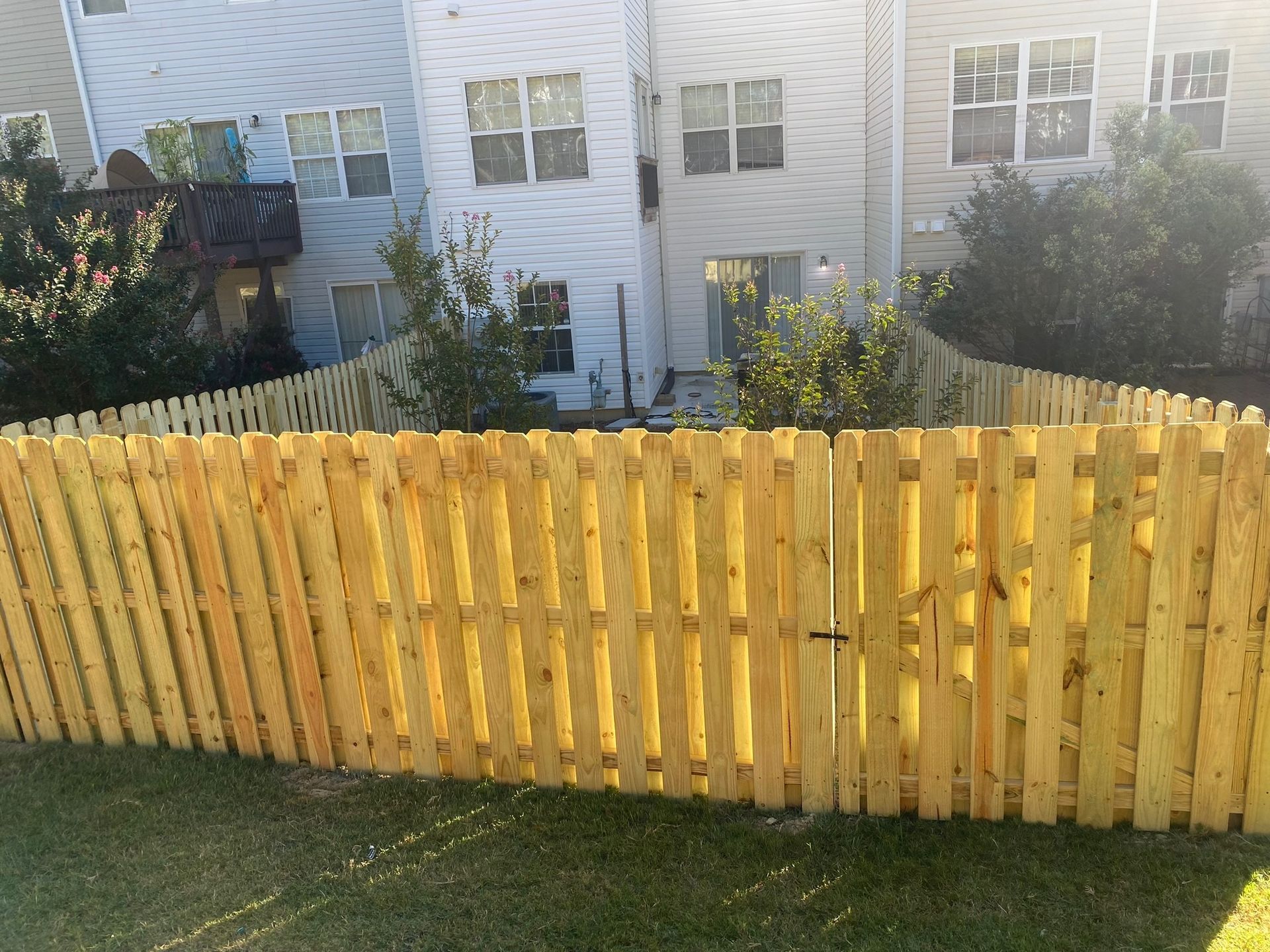 A wooden fence is in the backyard of a house.