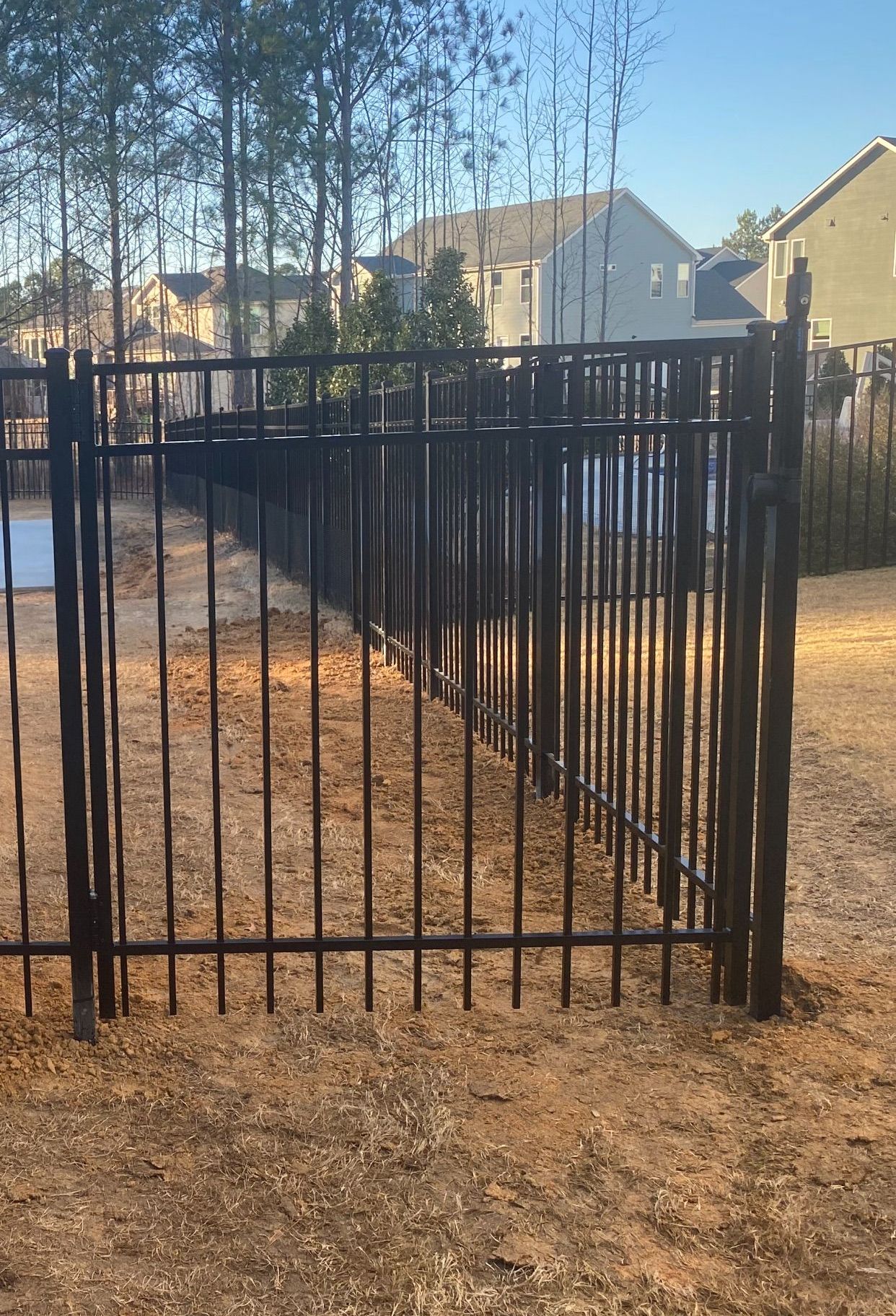 A black metal fence with a gate in the middle of a yard.