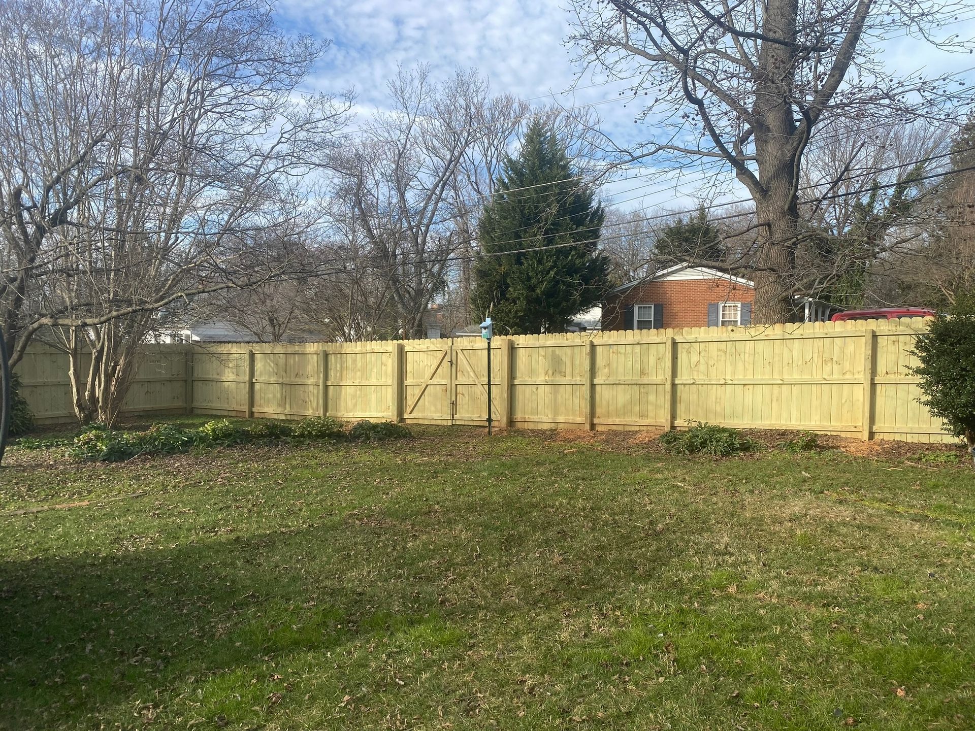 A wooden fence is in the middle of a lush green yard.
