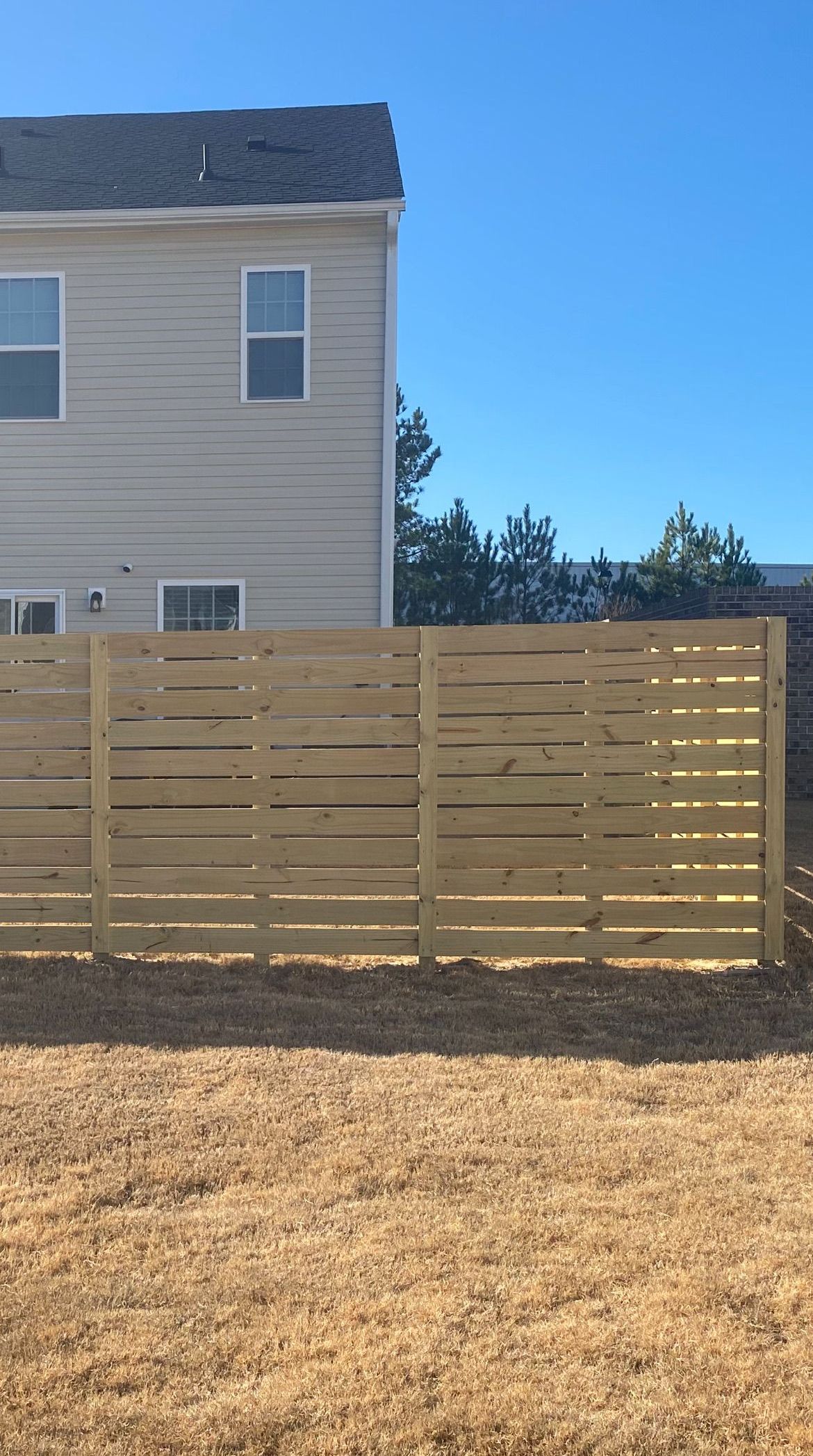 A wooden fence is in the backyard of a house.