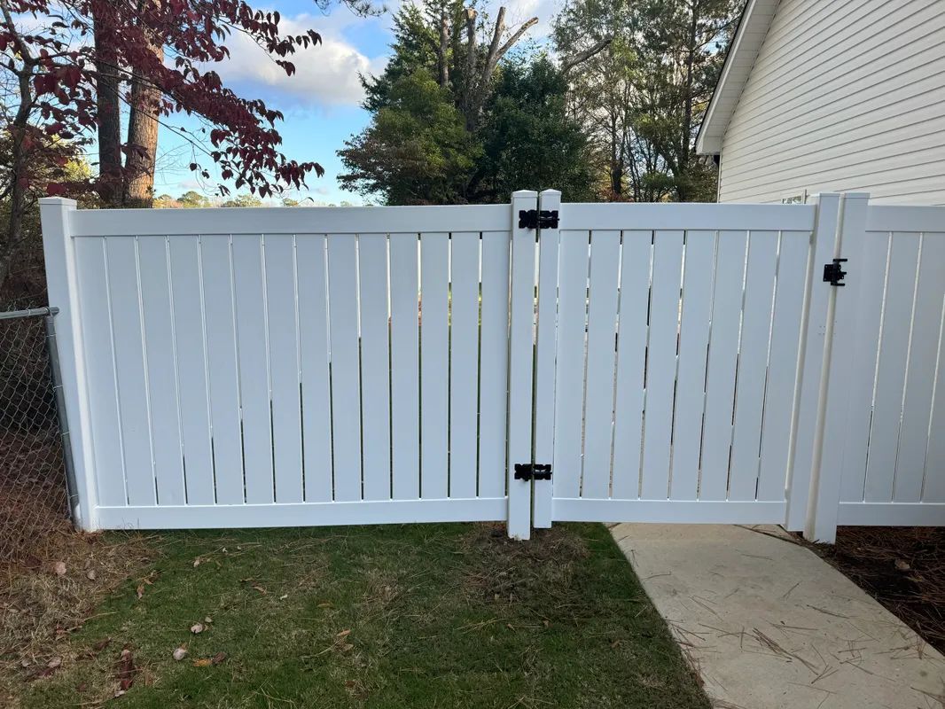 A white fence with a gate in front of a house.